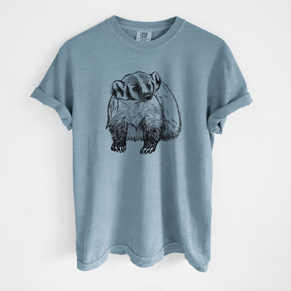 Steel blue Comfort Colors t-shirt laid flat, printed with a detailed black ink illustration of an American badger facing forward.