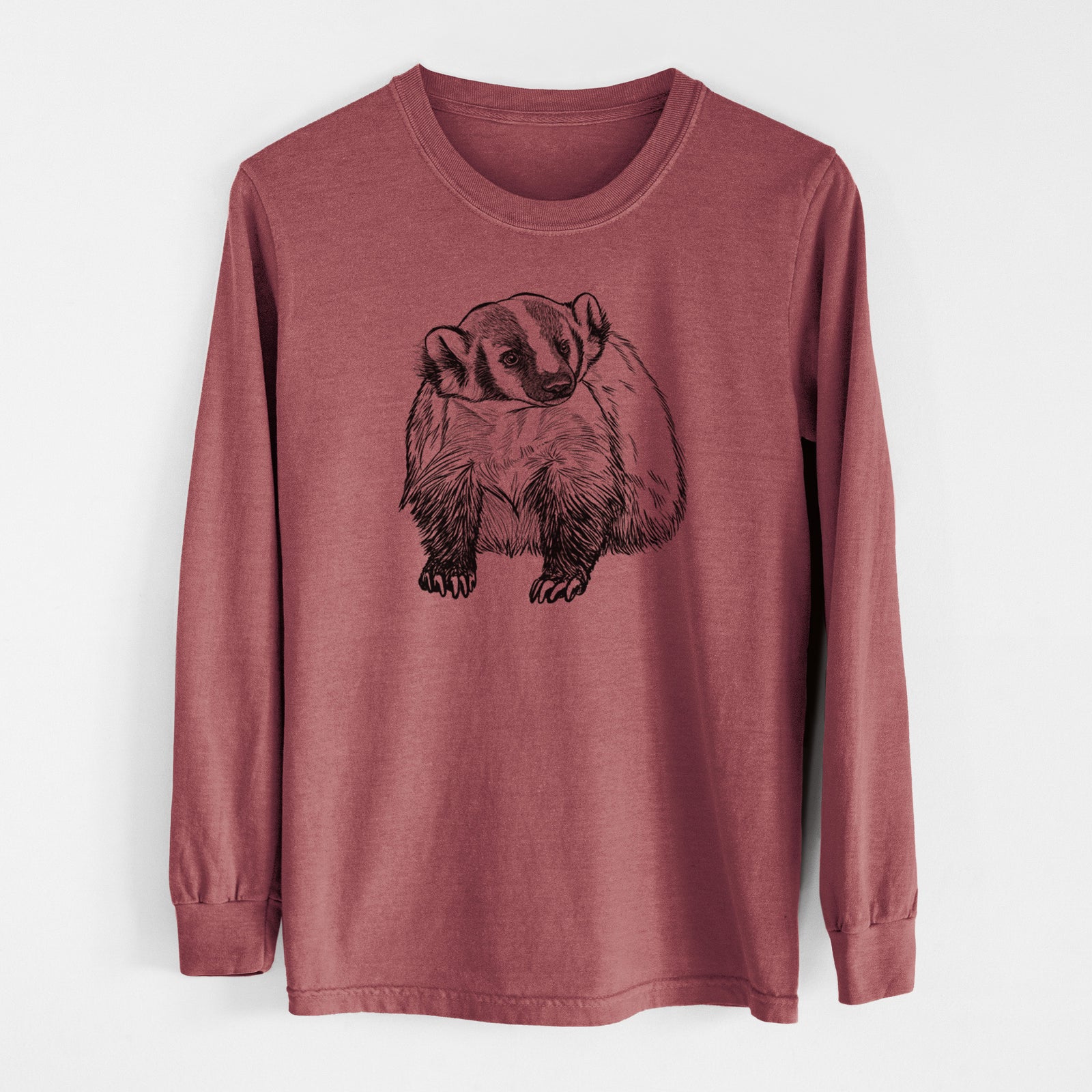 Ivory Comfort Colors long sleeve shirt laid flat, printed with a detailed black ink illustration of an American badger facing forward.