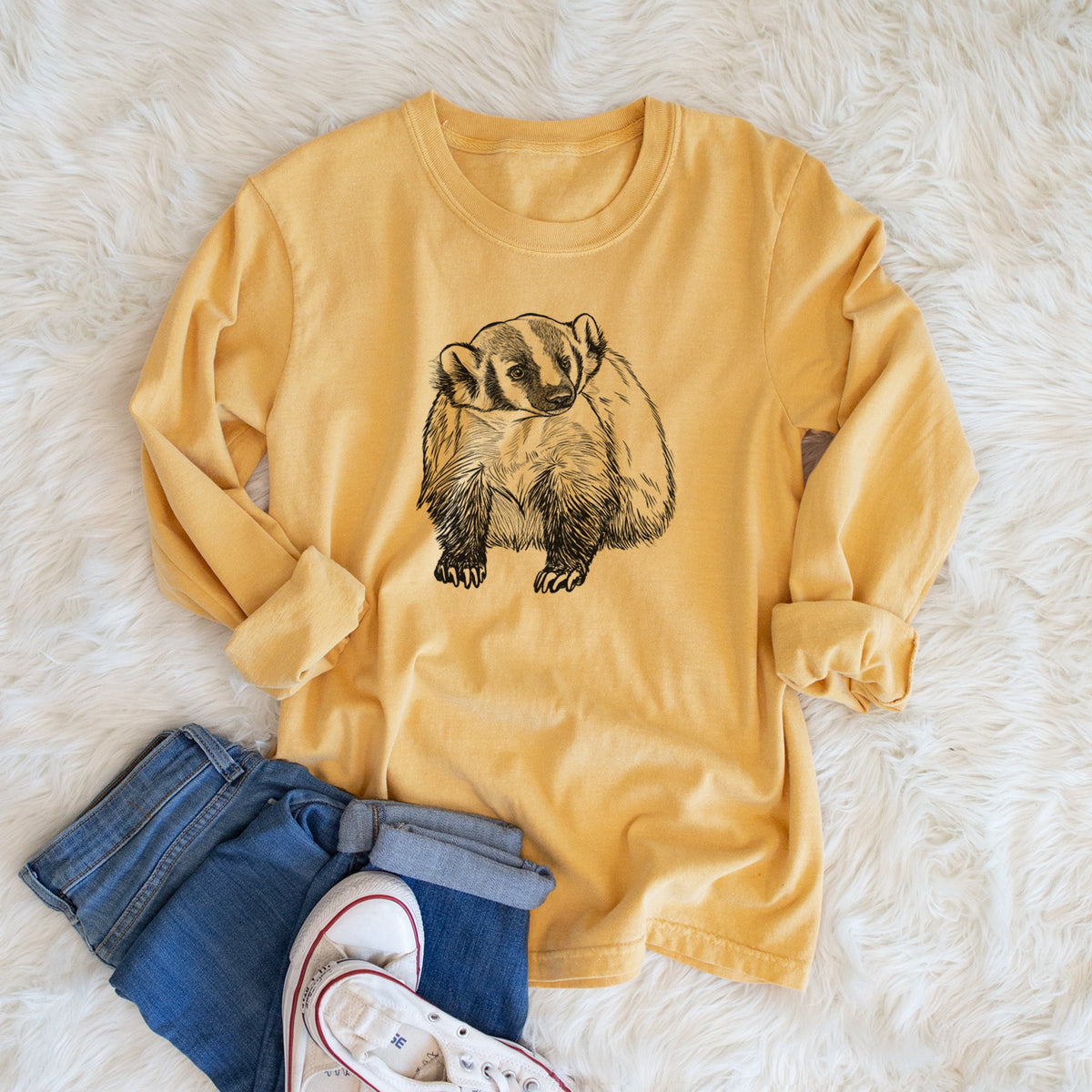 Golden wheat yellow Comfort Colors long sleeve shirt printed with a detailed black ink illustration of an American badger facing forward, shown in a lifestyle photo.