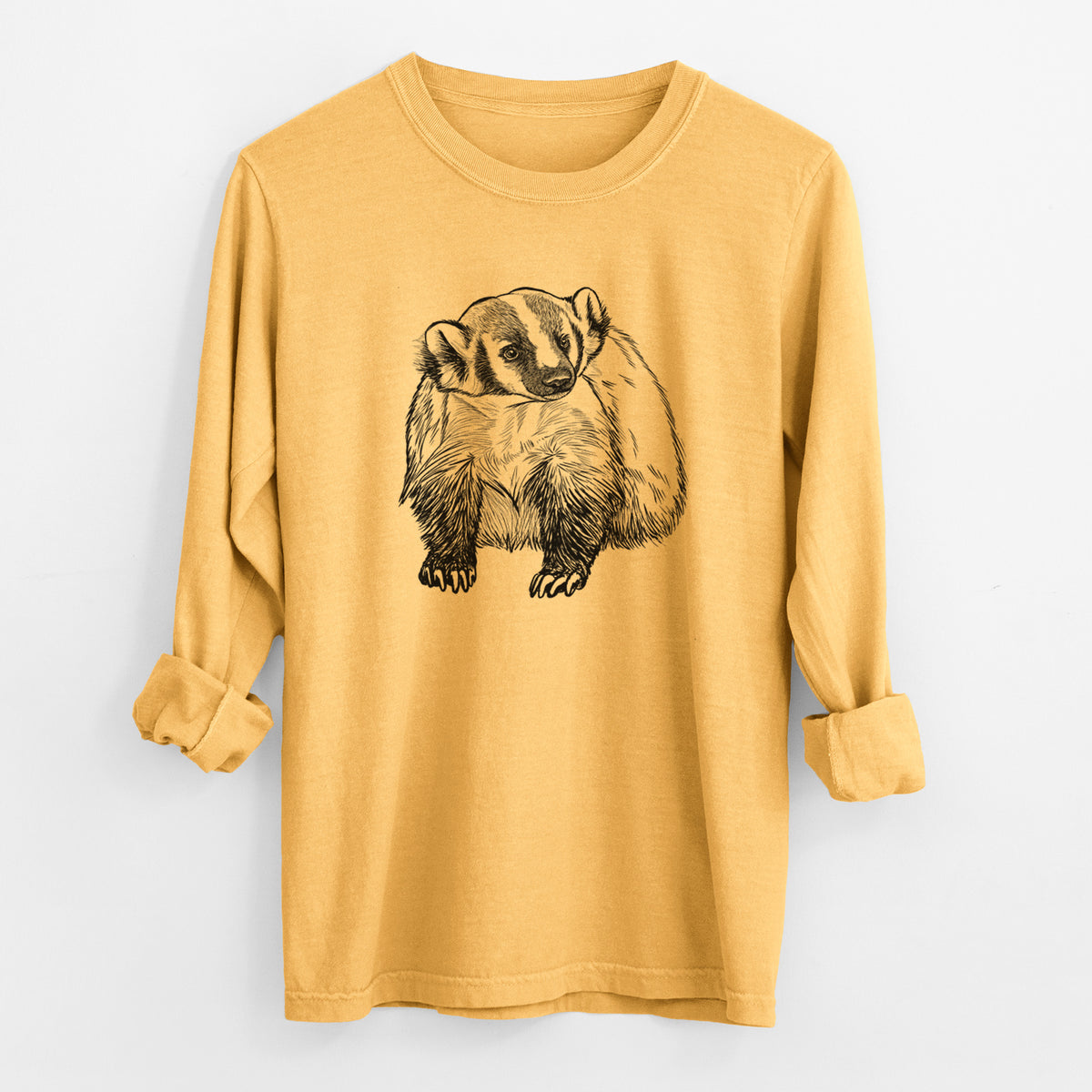 Golden wheat yellow Comfort Colors long sleeve shirt laid flat with the cuffs rolled, printed with a detailed black ink illustration of an American badger facing forward.