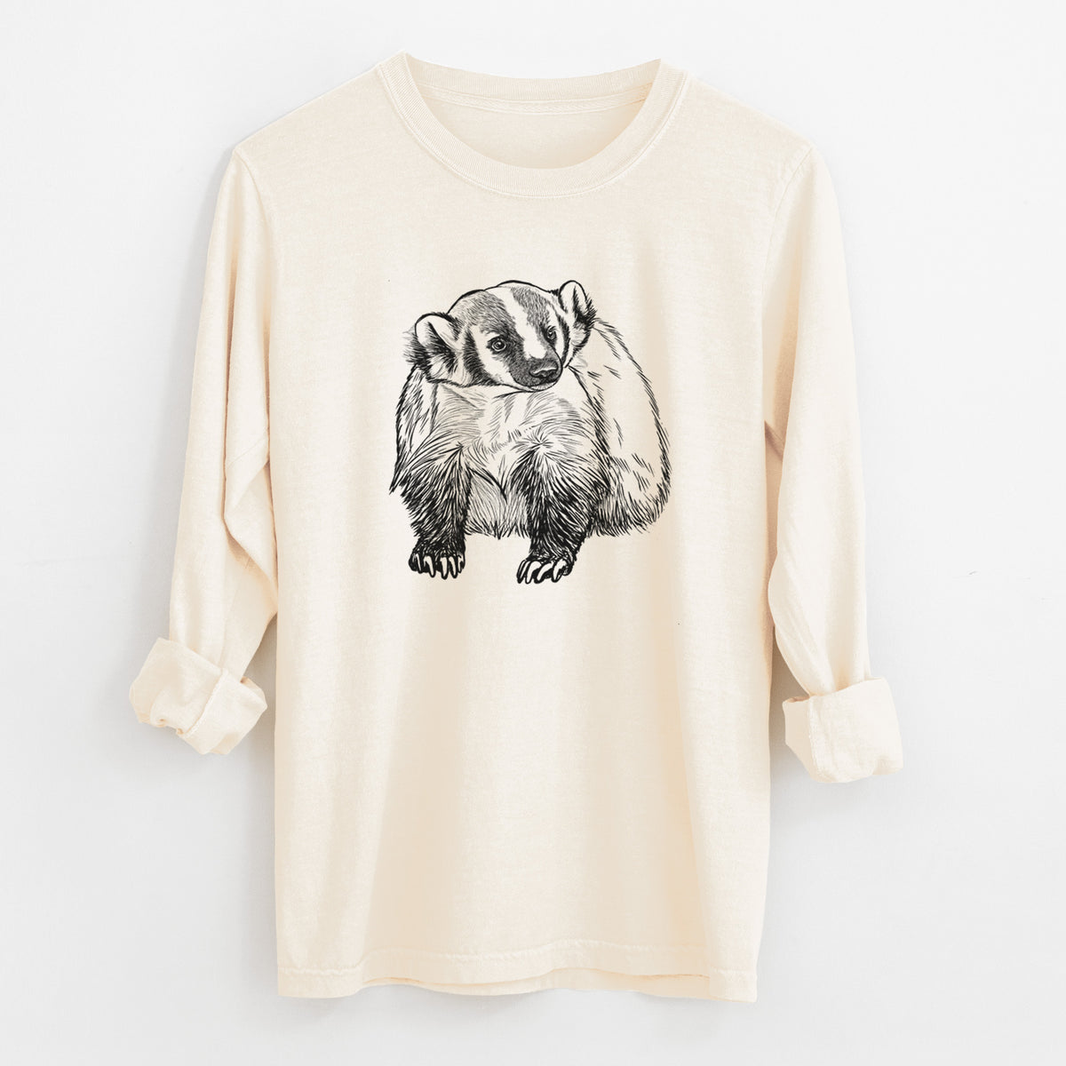Ivory Comfort Colors long sleeve shirt laid flat with the cuffs rolled, printed with a detailed black ink illustration of an American badger facing forward.