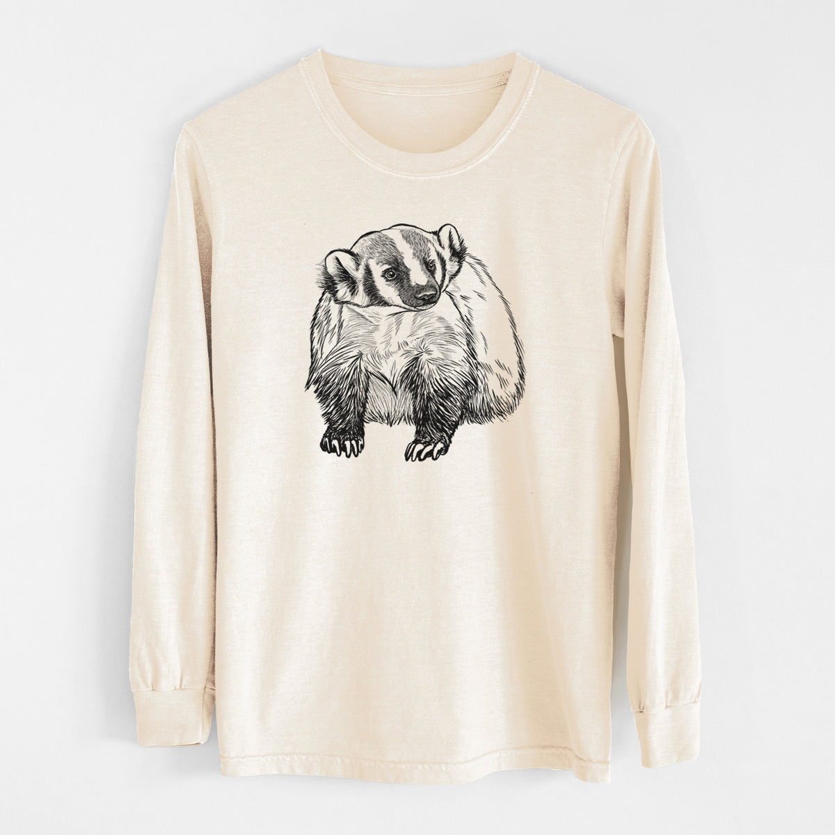 Ivory Comfort Colors long sleeve shirt laid flat, printed with a detailed black ink illustration of an American badger facing forward.