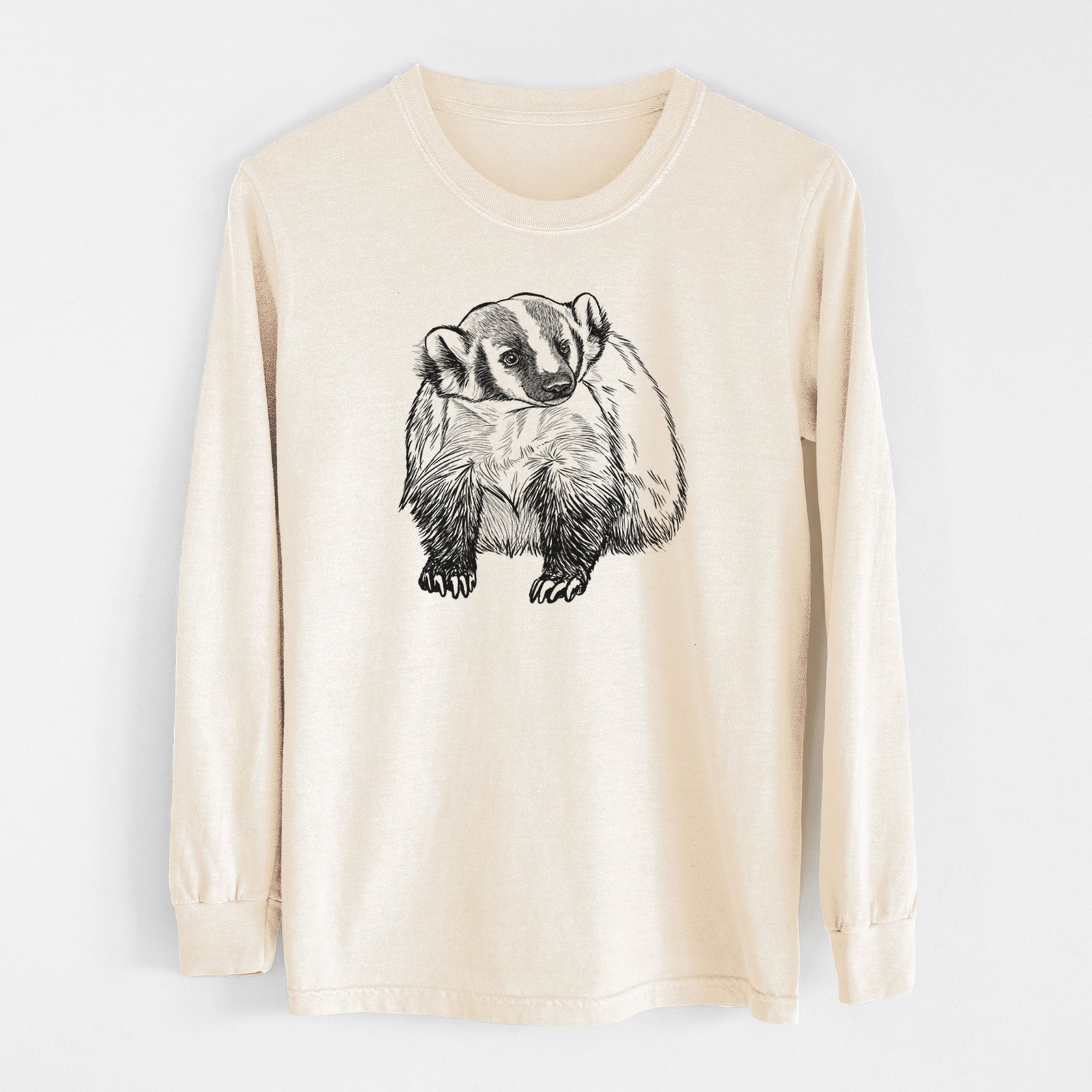 Ivory Comfort Colors long sleeve shirt laid flat, printed with a detailed black ink illustration of an American badger facing forward.