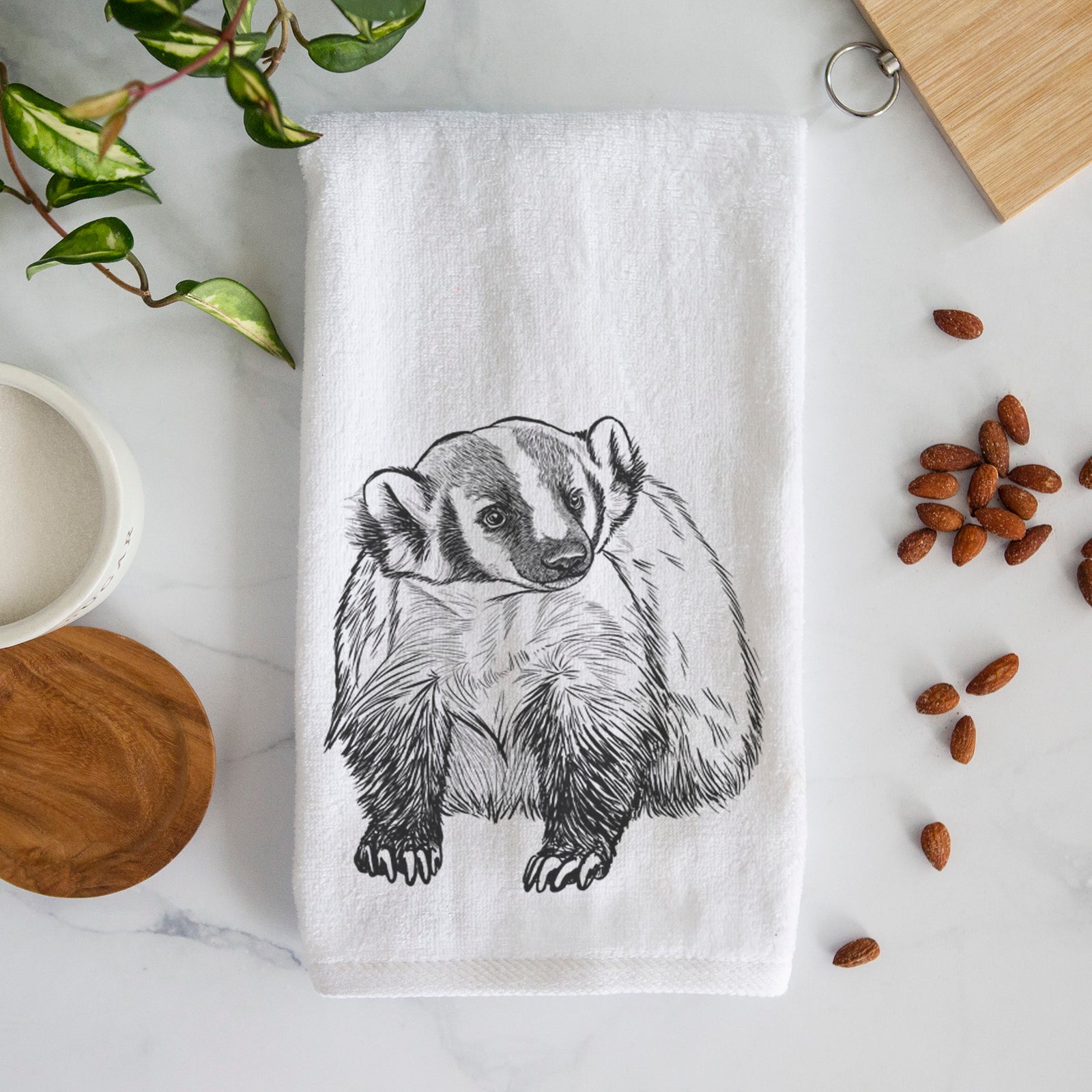 White hand towel printed with a detailed black ink illustration of an American badger facing forward.