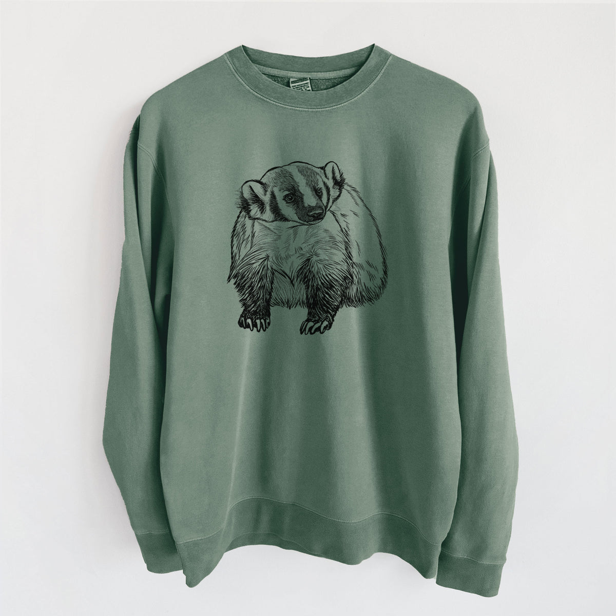 Alpine green pigment dyed crewneck sweatshirt laid flat, printed with a detailed black ink illustration of an American badger facing forward.