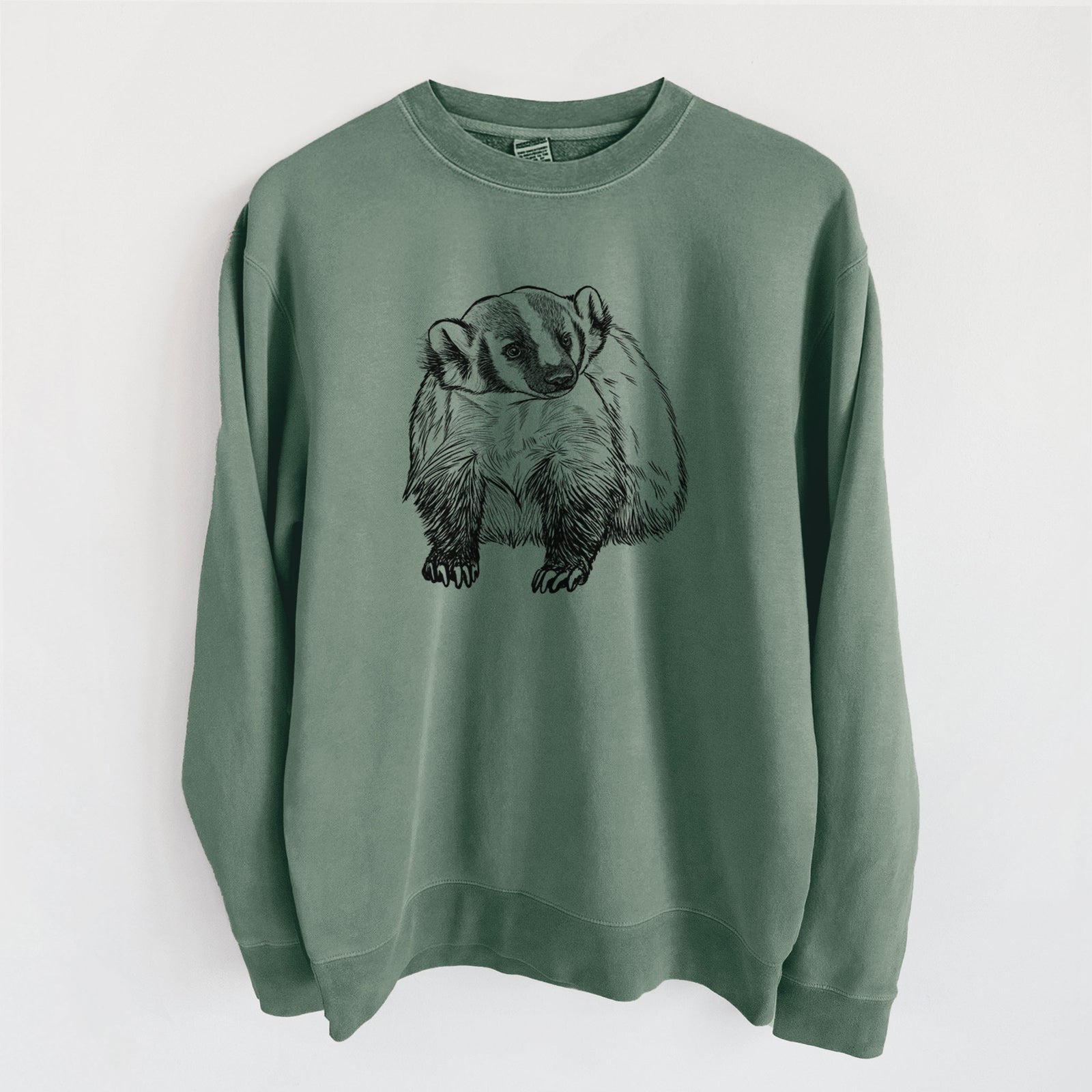 Alpine green pigment dyed crewneck sweatshirt laid flat, printed with a detailed black ink illustration of an American badger facing forward.