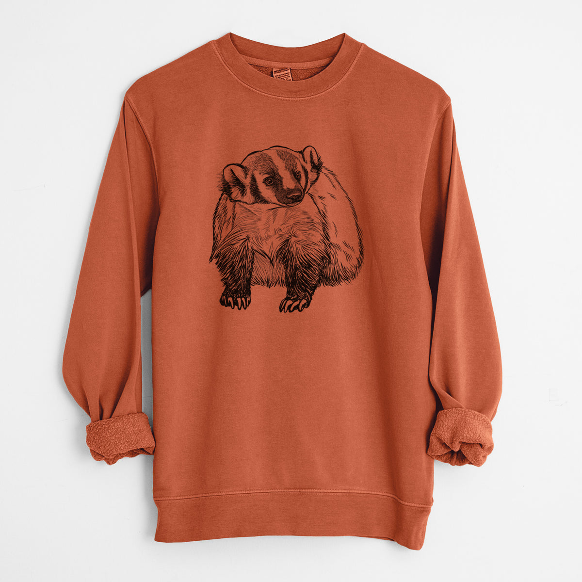 Amber orange pigment dyed crewneck sweatshirt laid flat with the sleeves rolled, printed with a detailed black ink illustration of an American badger facing forward.