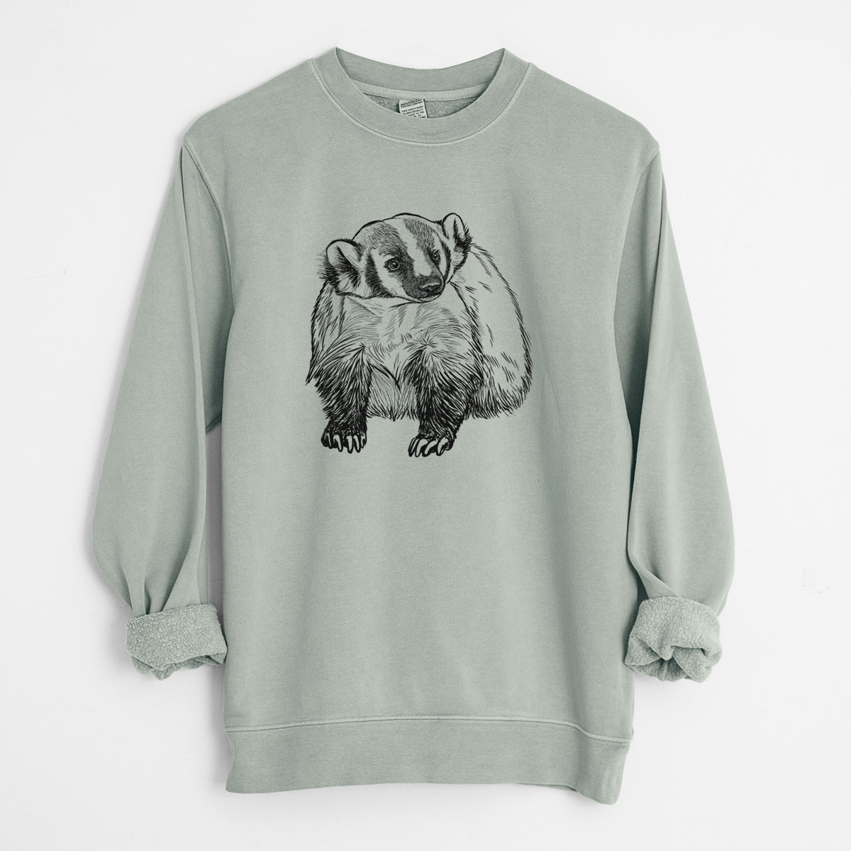 Sage green pigment dyed crewneck sweatshirt laid flat with the sleeves rolled, printed with a detailed black ink illustration of an American badger facing forward.
