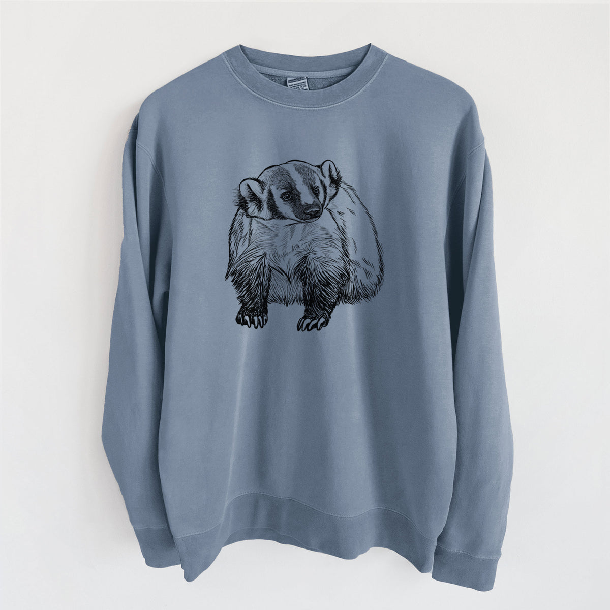 Slate blue pigment dyed crewneck sweatshirt laid flat, printed with a detailed black ink illustration of an American badger facing forward.