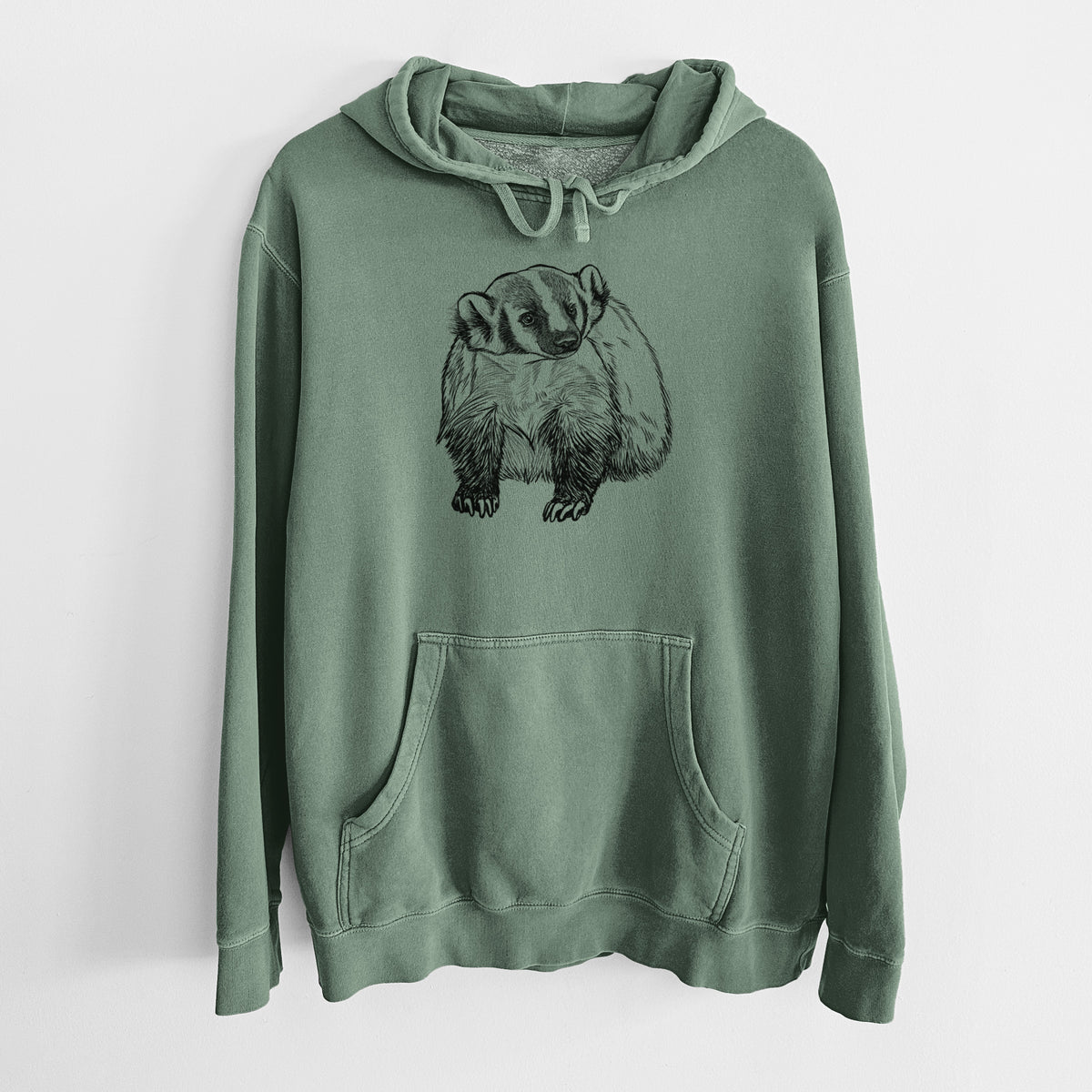 Alpine green pigment dyed hoodie laid flat, printed with a detailed black ink illustration of an American badger facing forward.