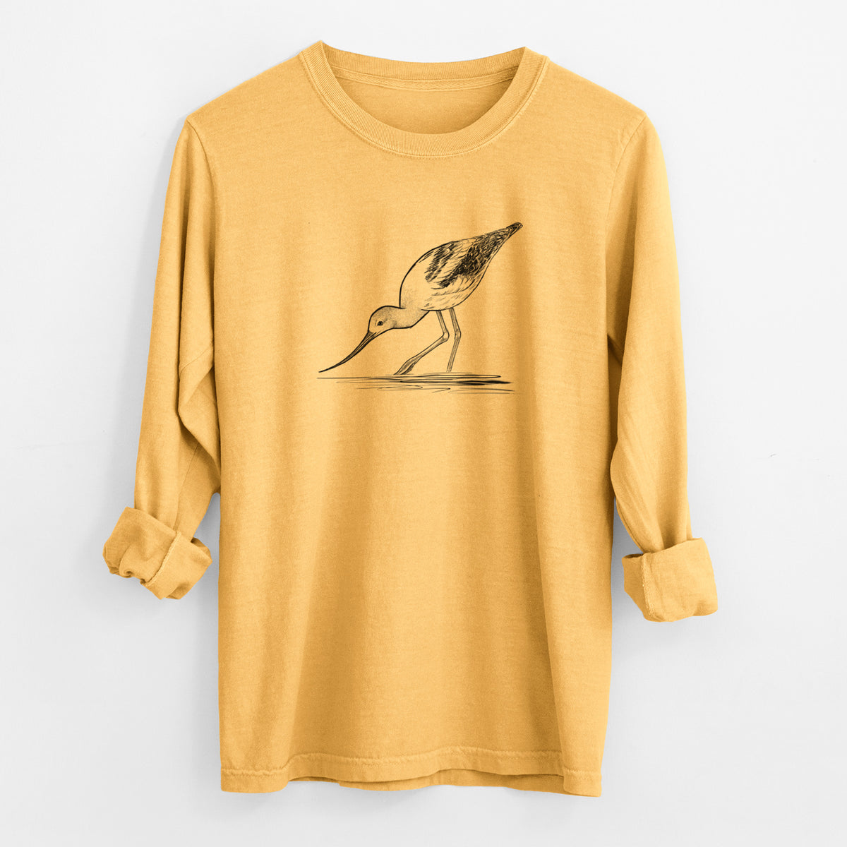Golden wheat yellow Comfort Colors long sleeve shirt laid flat with the cuffs rolled, printed with a detailed black ink sketch of an American avocet wading in shallow water.