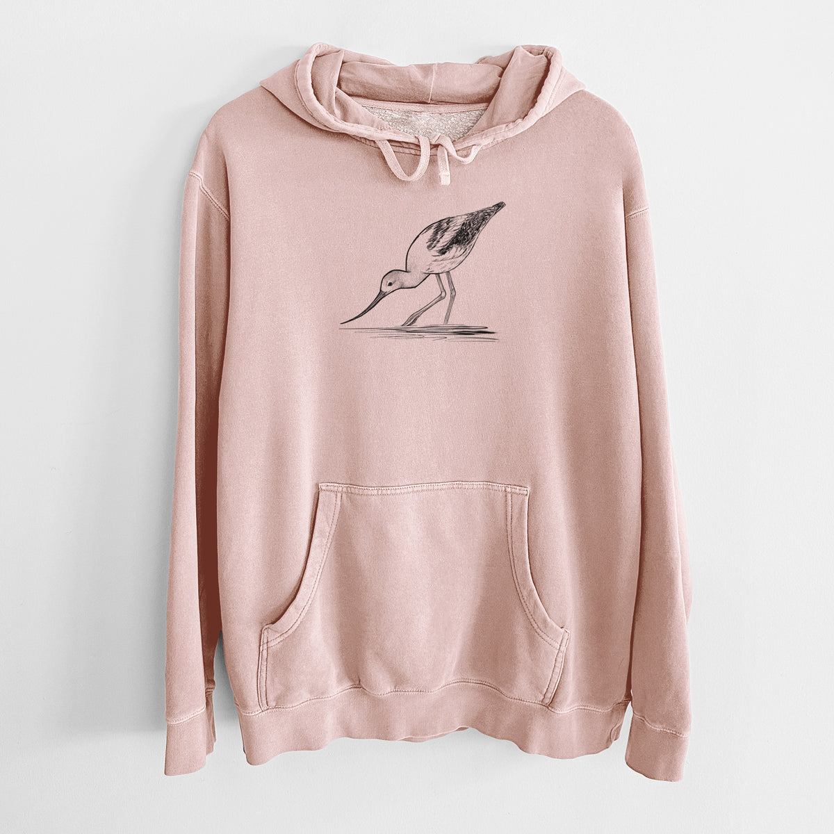 Dusty pink pigment dyed hoodie laid flat, printed with a detailed black ink sketch of an American avocet wading in shallow water.