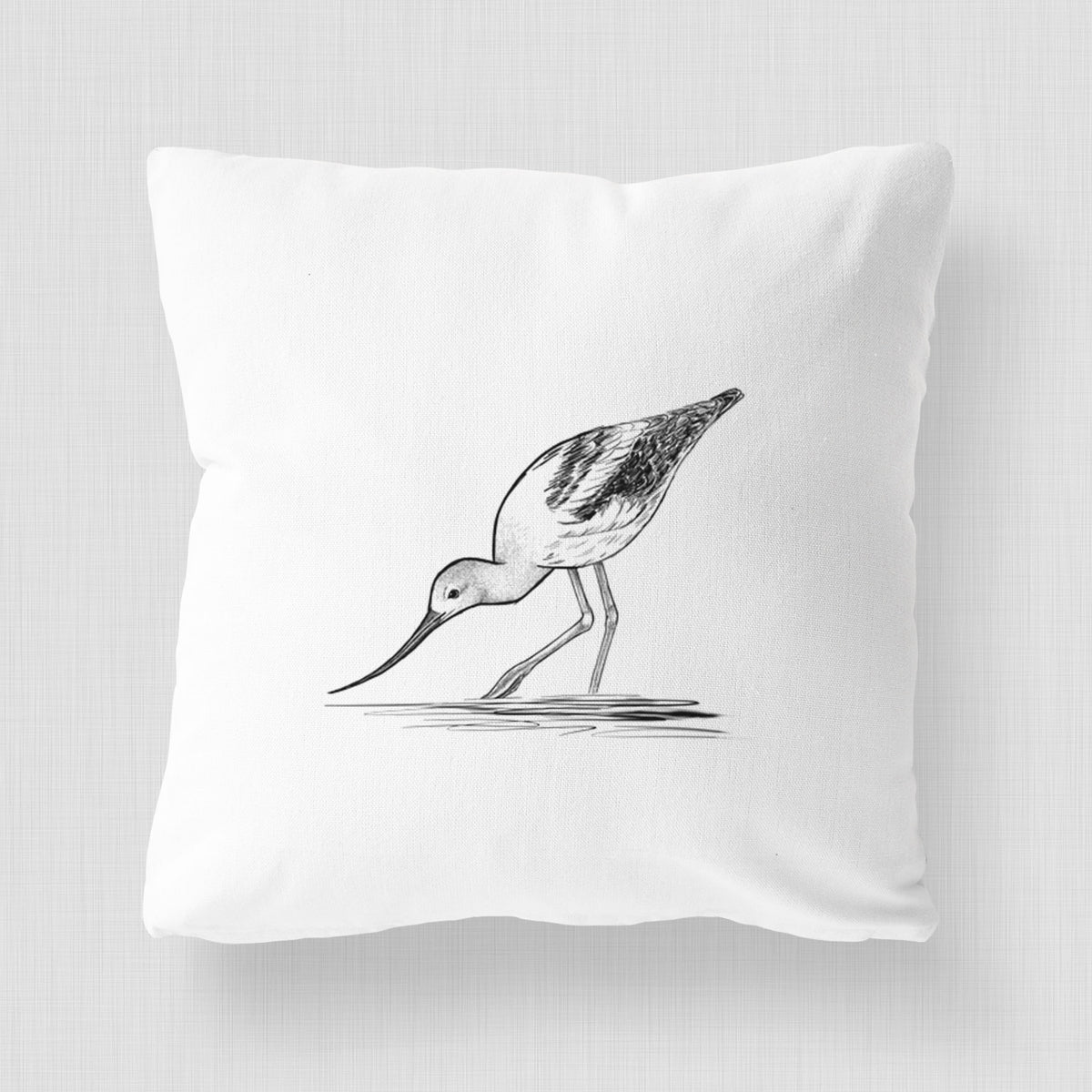 White pillow cover printed with a detailed black ink sketch of an American avocet wading in shallow water.