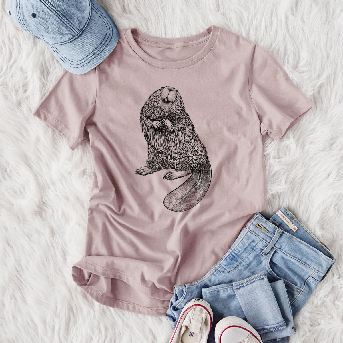 Women's relaxed fit cotton t-shirt printed with a detailed black ink illustration of an American beaver sitting upright with its flat tail, styled flat on a white faux fur rug with jeans.