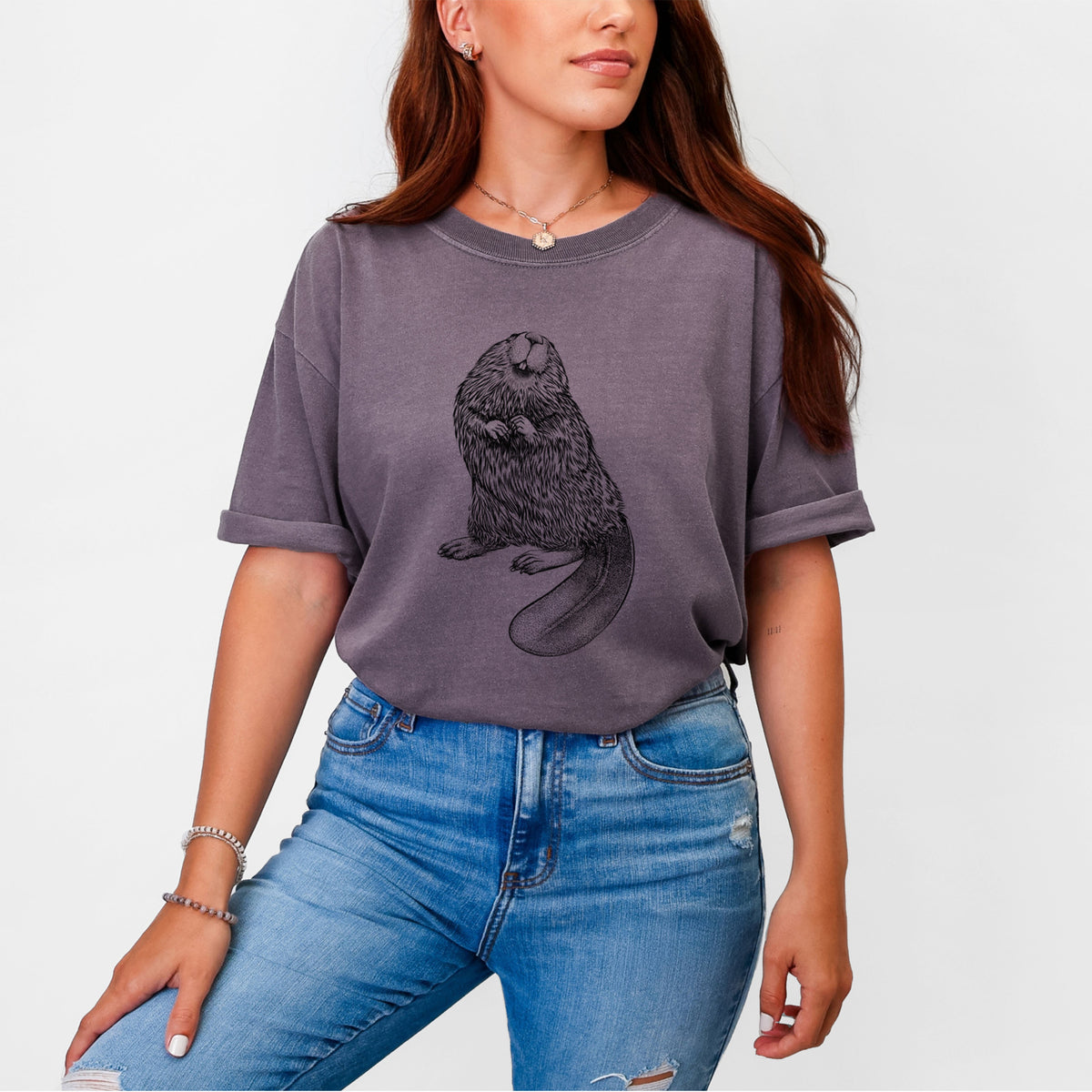 Woman wearing a Comfort Colors t-shirt printed with a detailed black ink illustration of an American beaver sitting upright with its flat tail.
