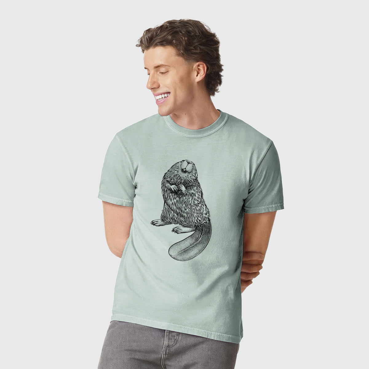 Man wearing a Comfort Colors t-shirt printed with a detailed black ink illustration of an American beaver sitting upright with its flat tail.