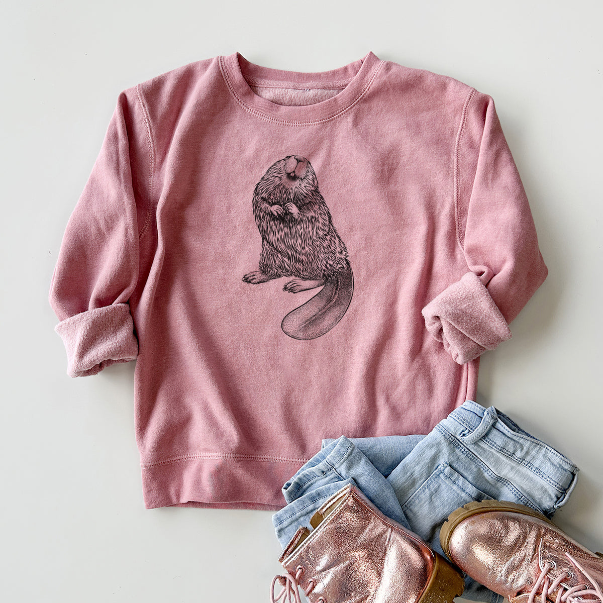 Youth crewneck sweatshirt printed with a detailed black ink illustration of an American beaver sitting upright with its flat tail, styled flat with jeans and boots.