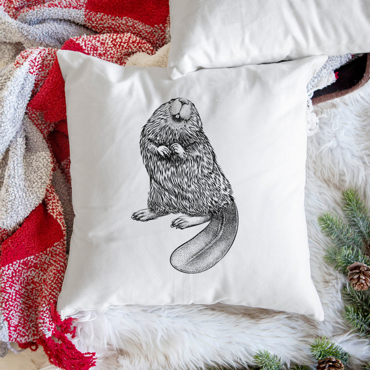 White pillow cover printed with a detailed black ink illustration of an American beaver sitting upright with its flat tail, on a woven chair.