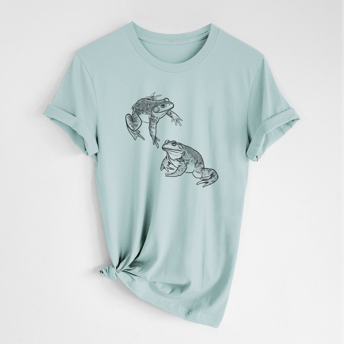 Dusty blue lightweight cotton t-shirt laid flat with the sleeves rolled, printed with a detailed black ink illustration of two American bullfrogs.
