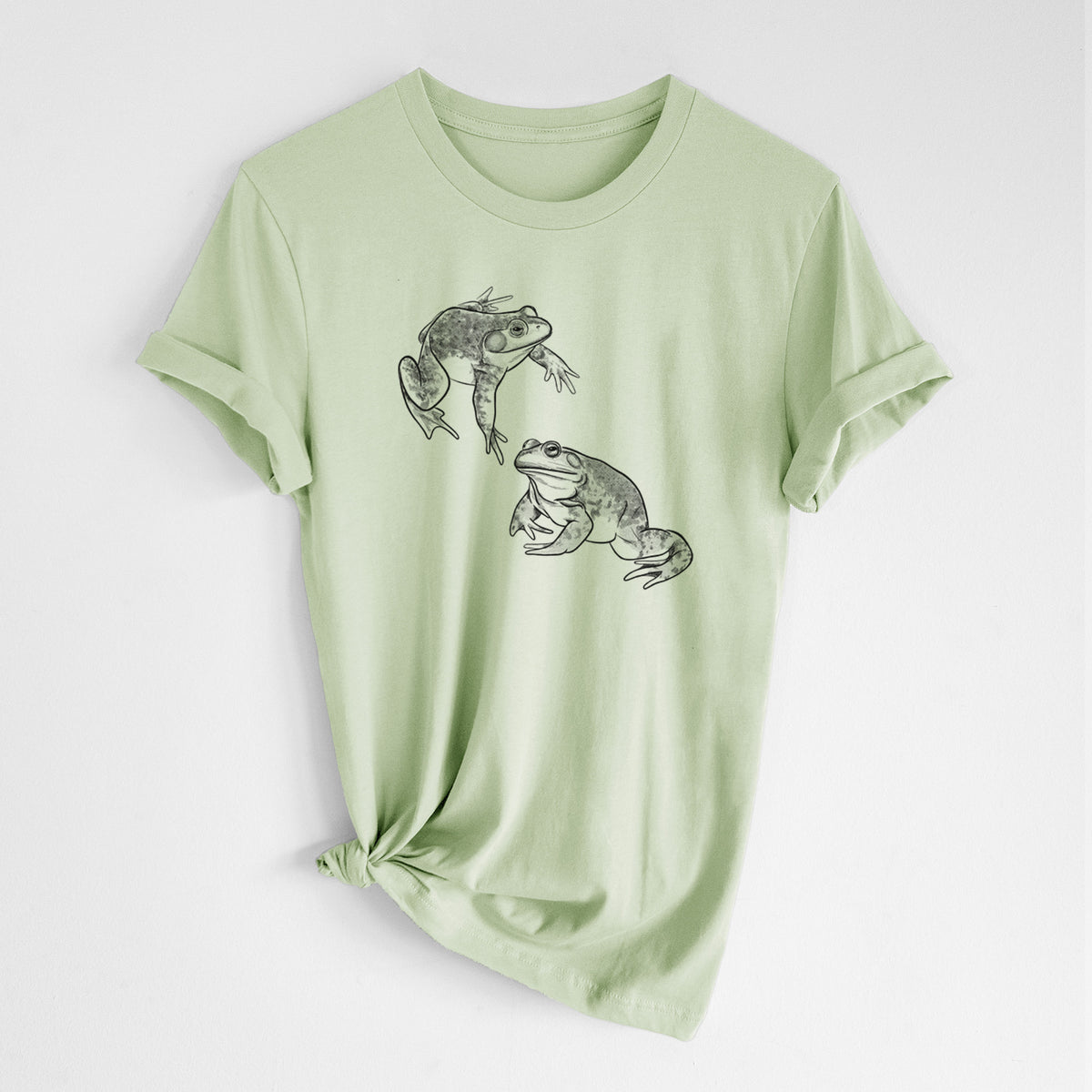 Spring green lightweight cotton t-shirt laid flat with the sleeves rolled, printed with a detailed black ink illustration of two American bullfrogs.