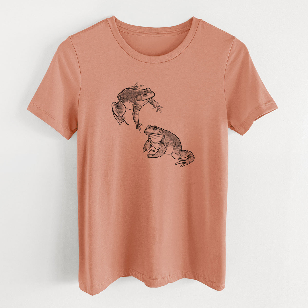 Terracotta orange women's relaxed fit cotton t-shirt laid flat, printed with a detailed black ink illustration of two American bullfrogs.