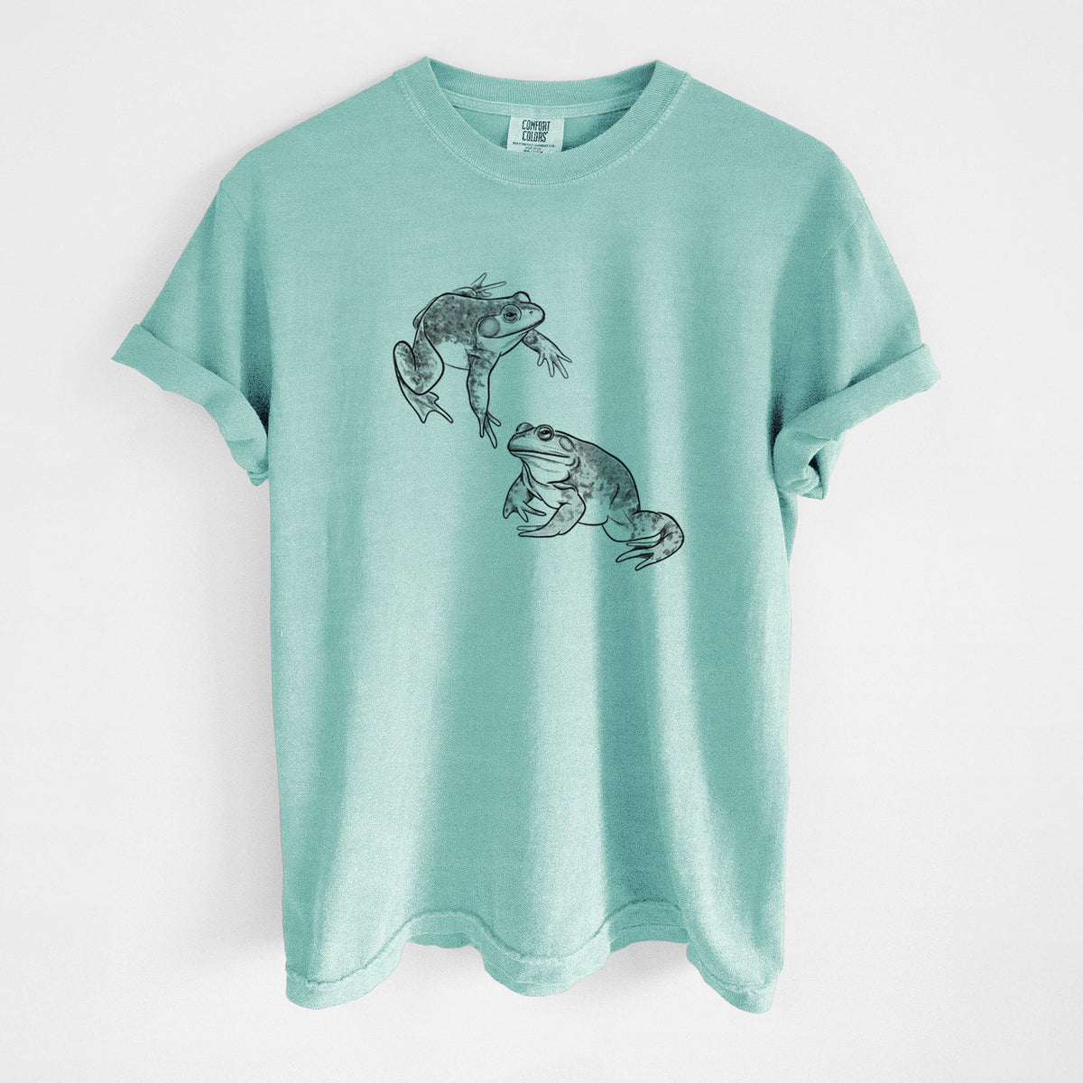 Chalky mint Comfort Colors t-shirt laid flat, printed with a detailed black ink illustration of two American bullfrogs.