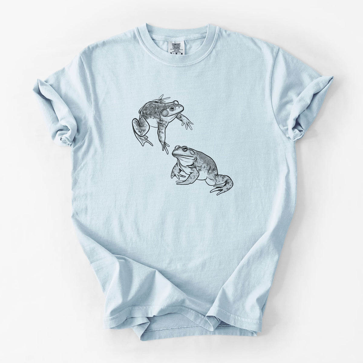 Chambray blue Comfort Colors t-shirt laid flat, printed with a detailed black ink illustration of two American bullfrogs.