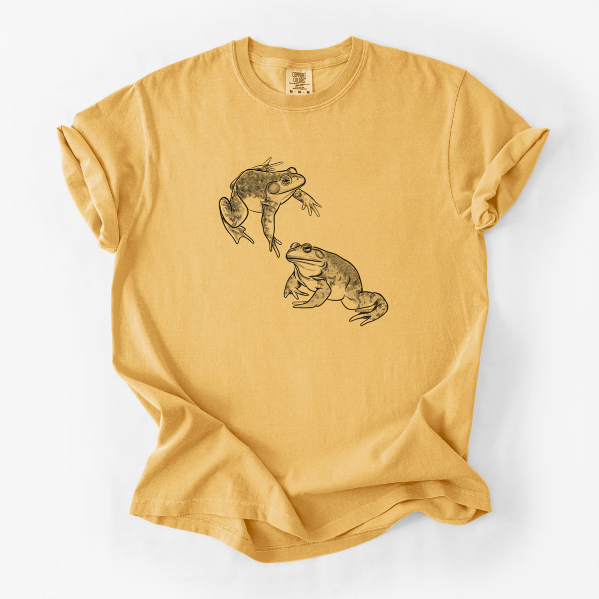 Golden wheat yellow Comfort Colors t-shirt laid flat, printed with a detailed black ink illustration of two American bullfrogs.