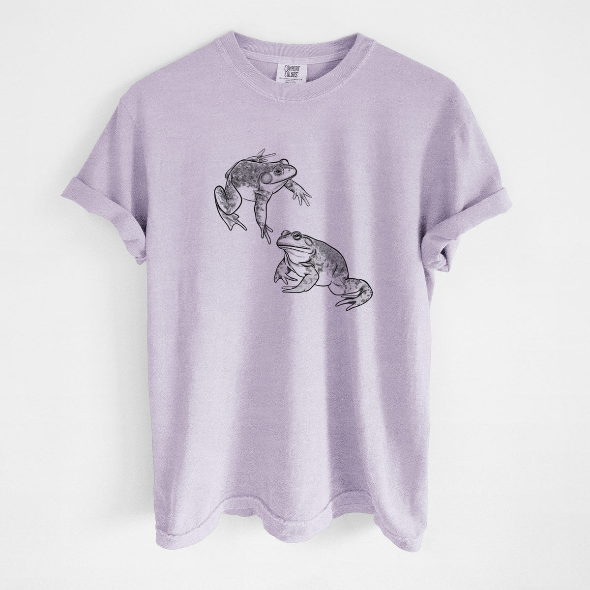 Orchid purple Comfort Colors t-shirt laid flat, printed with a detailed black ink illustration of two American bullfrogs.