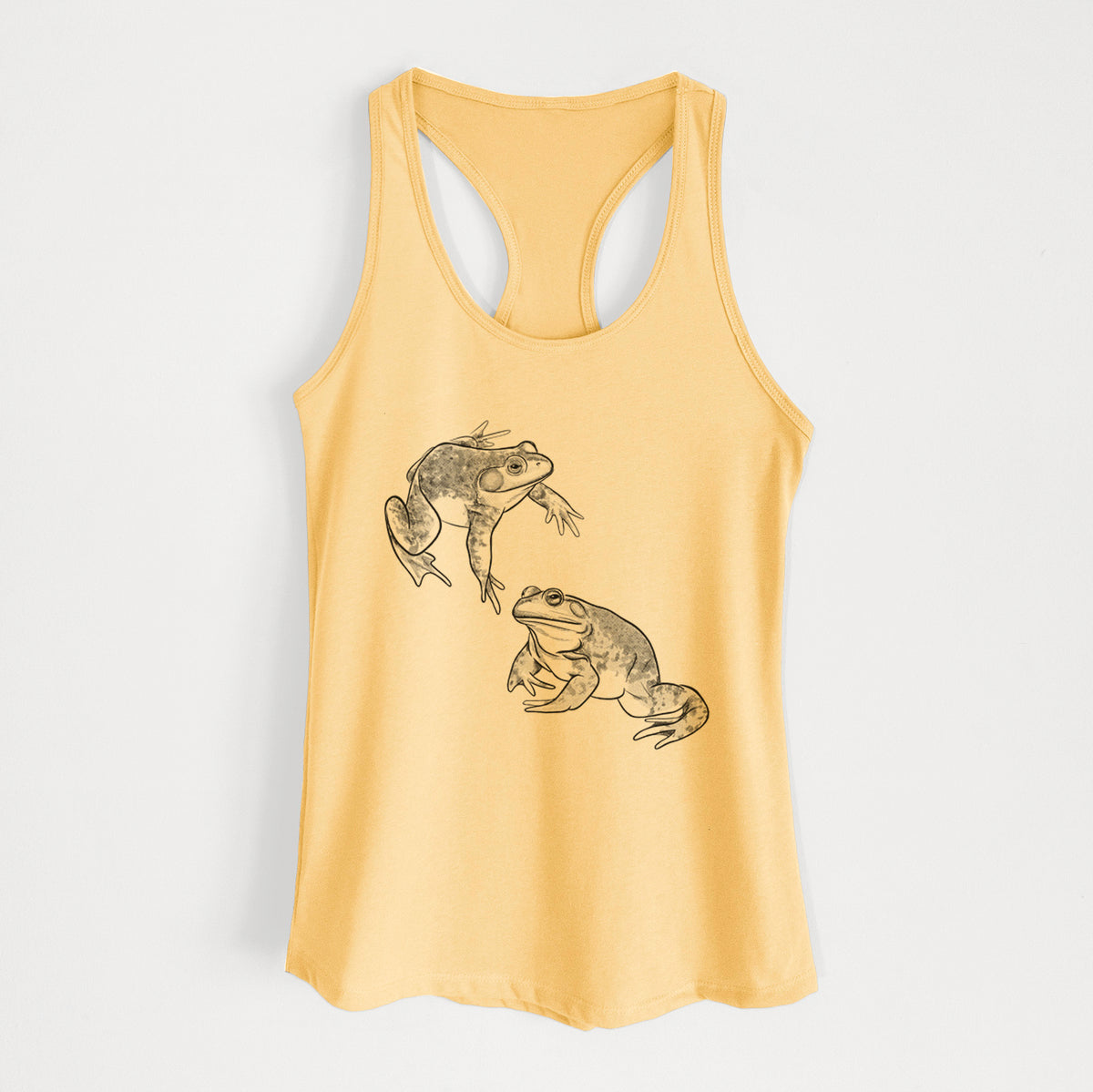 Banana cream women's racerback tank top laid flat, printed with a detailed black ink illustration of two American bullfrogs.