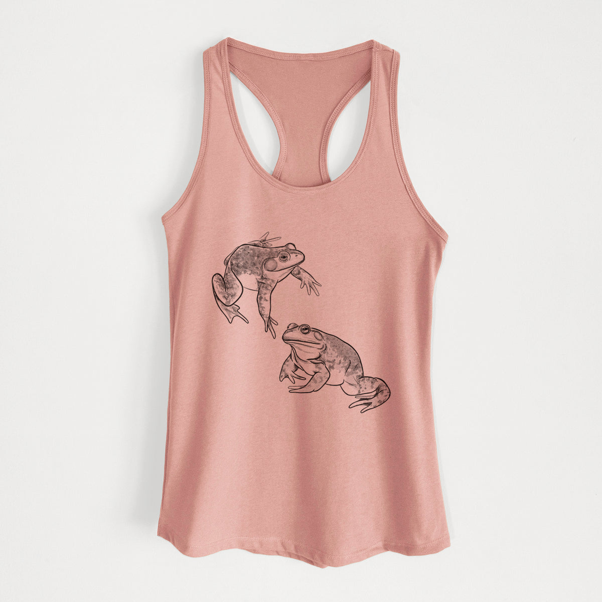 Desert pink women's racerback tank top laid flat, printed with a detailed black ink illustration of two American bullfrogs.