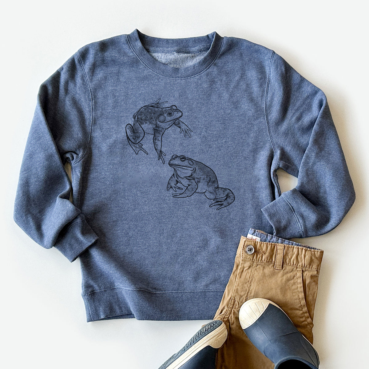 Youth crewneck sweatshirt printed with a detailed black ink illustration of two American bullfrogs, styled flat with khaki pants and shoes.