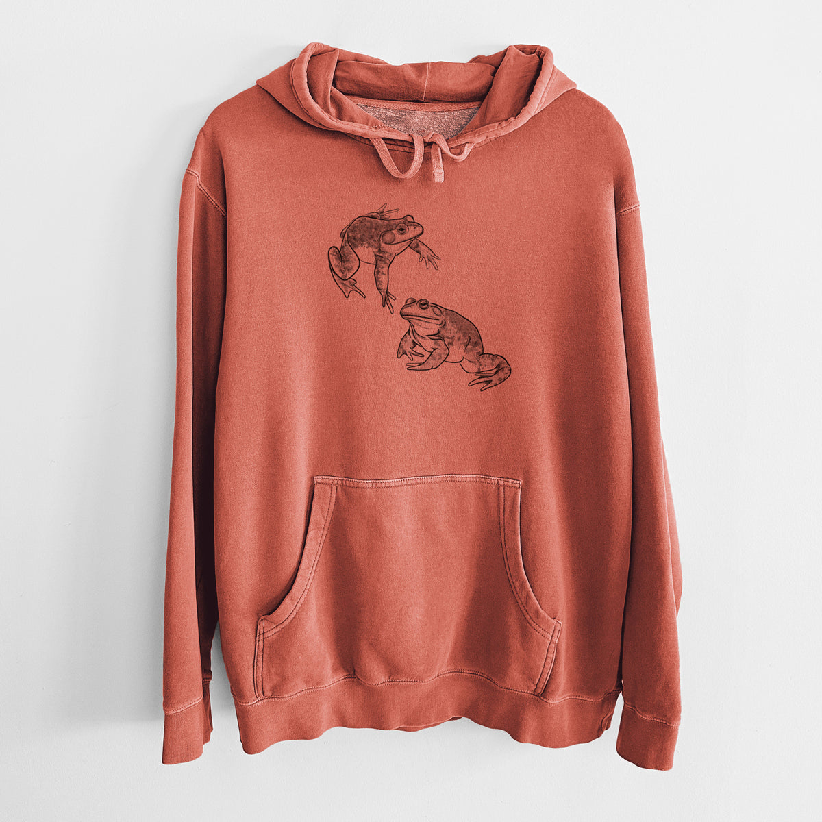 Amber orange pigment dyed hoodie laid flat, printed with a detailed black ink illustration of two American bullfrogs.