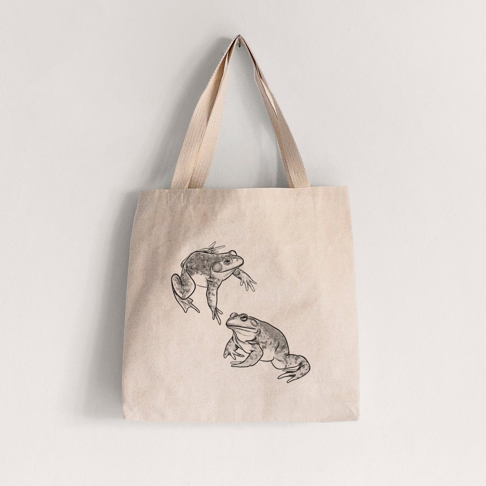 Natural canvas tote bag printed with a detailed black ink illustration of two American bullfrogs.