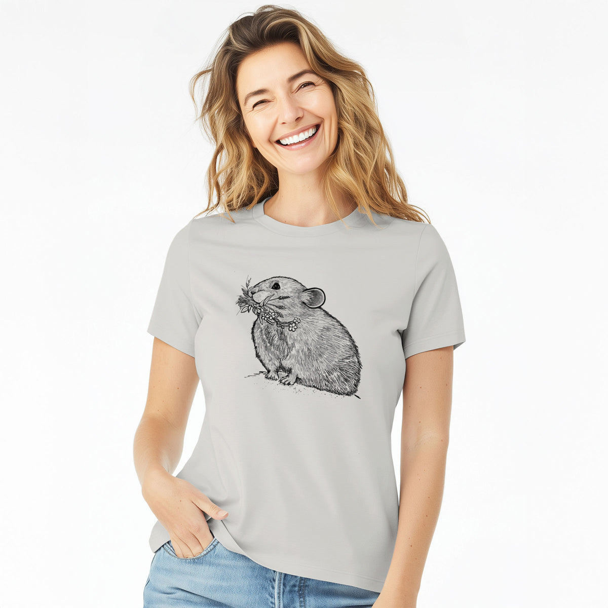 Woman wearing a lunar grey women's relaxed fit cotton t-shirt printed with a detailed black ink illustration of an American pika holding flowers and grass in its mouth.