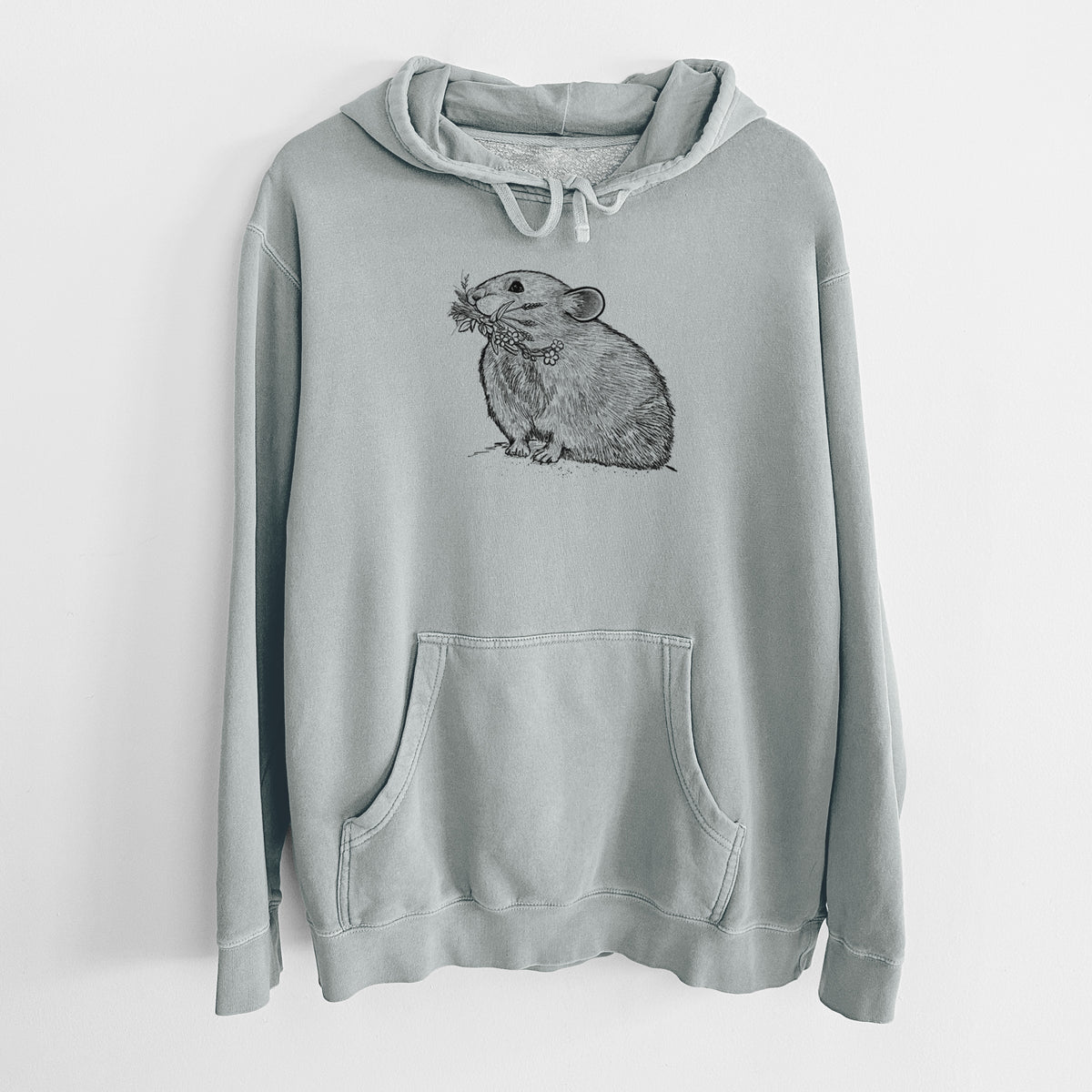 Sage green pigment dyed hoodie laid flat, printed with a detailed black ink illustration of an American pika holding flowers and grass in its mouth.