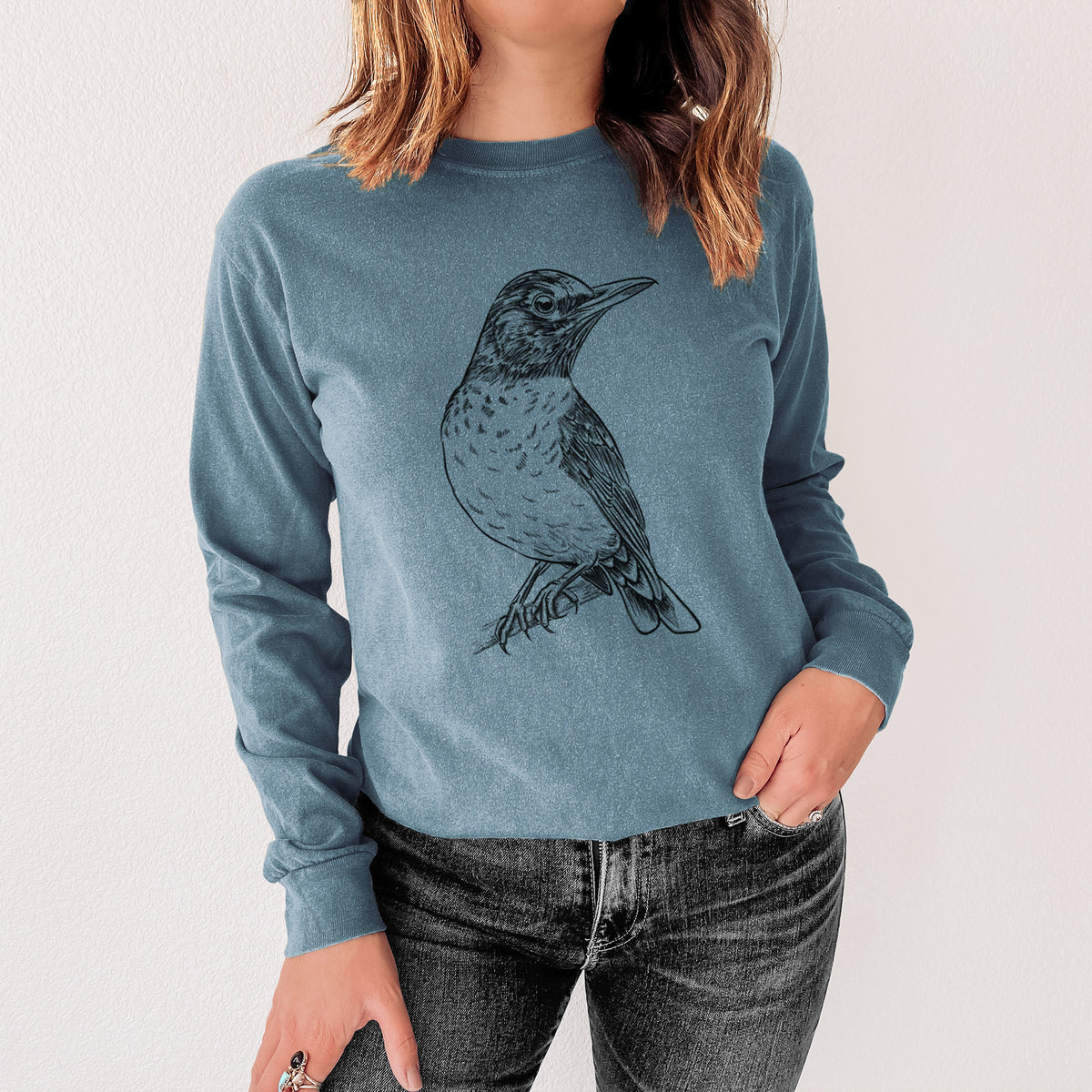 Steel blue Comfort Colors long sleeve shirt printed with a detailed black ink sketch of an American robin perched on a branch, shown in a lifestyle photo.