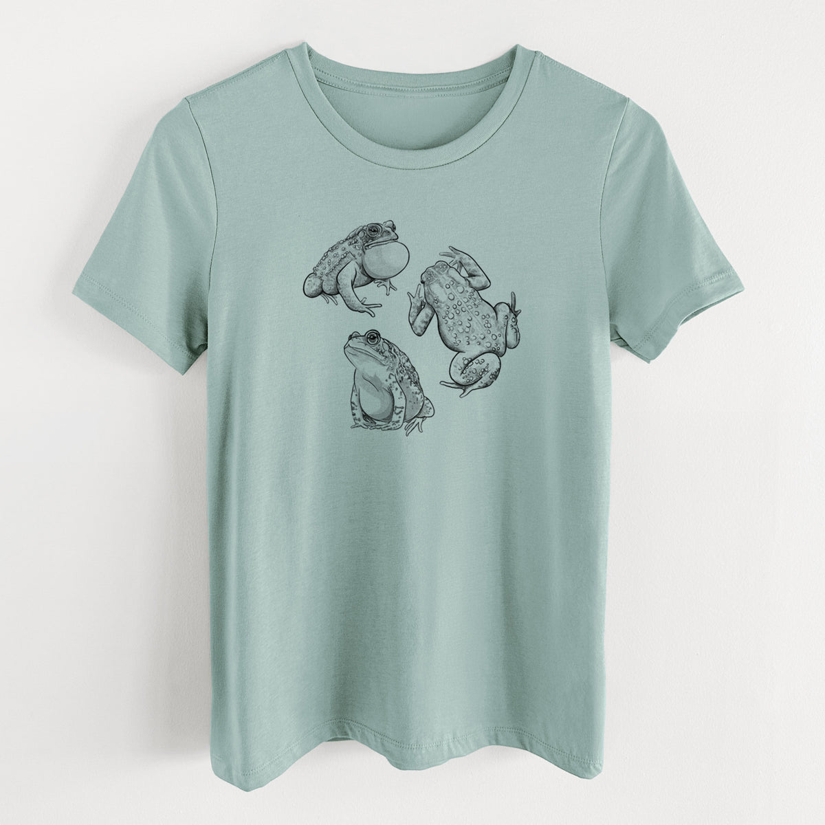 Dusty blue women's relaxed fit cotton t-shirt laid flat, printed with a black ink illustration of three American toads.
