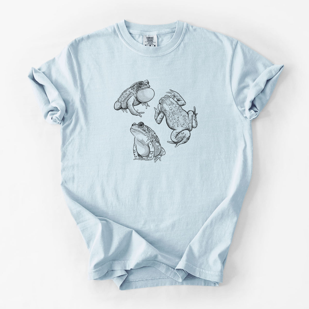 Chambray blue Comfort Colors t-shirt laid flat, printed with a black ink illustration of three American toads.