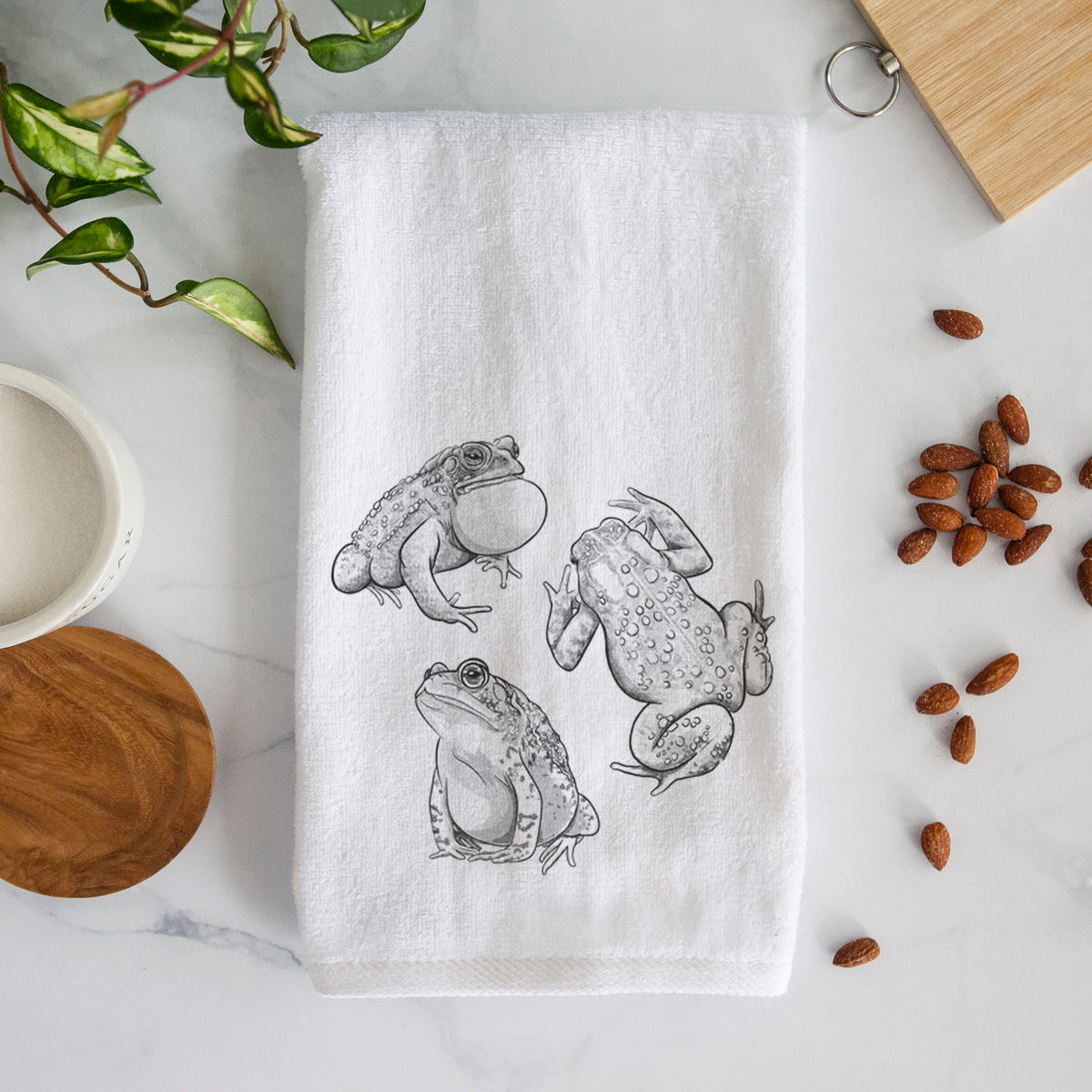 White hand towel printed with a black ink illustration of three American toads.
