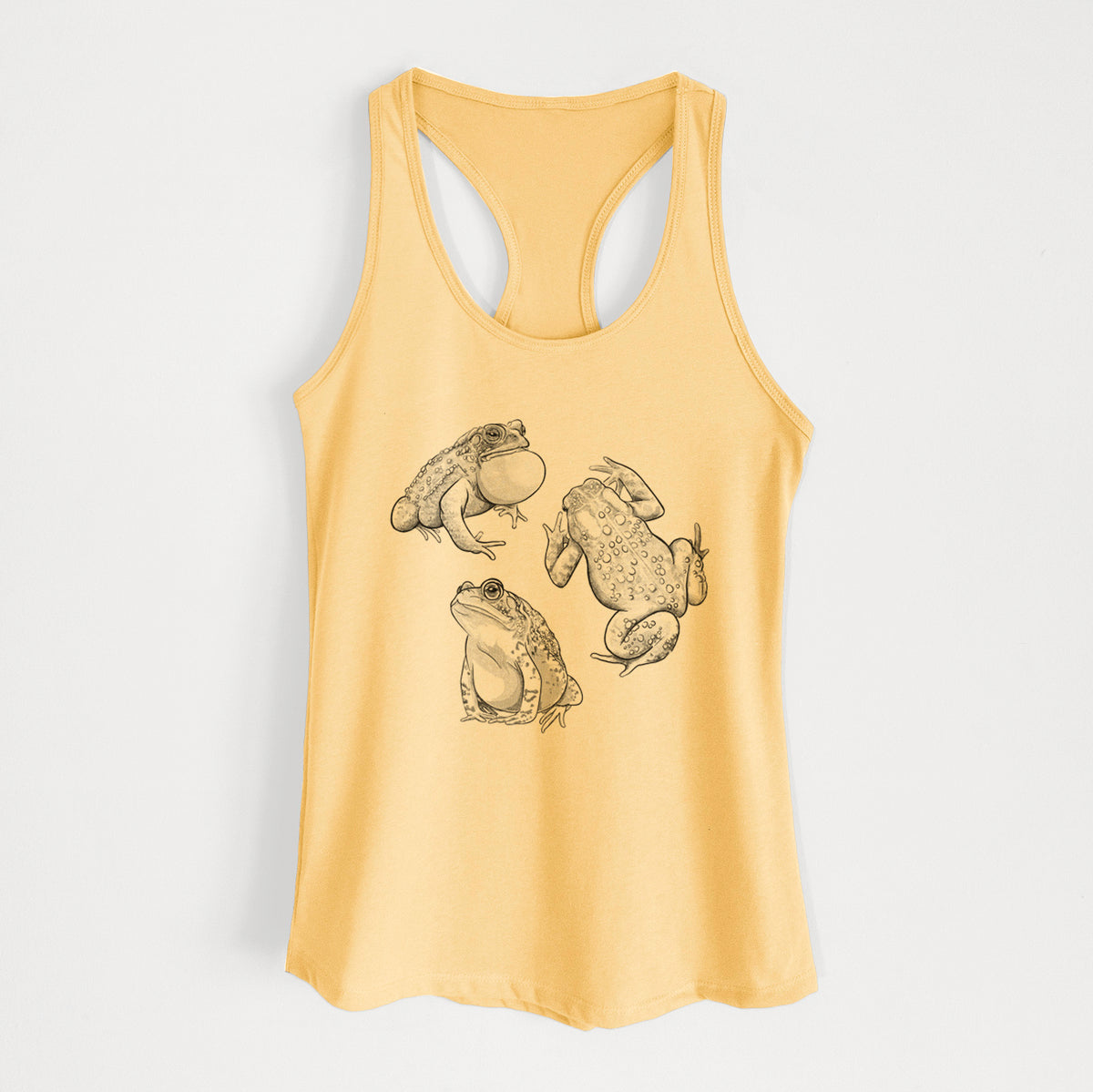 Banana cream women's racerback tank top laid flat, printed with a black ink illustration of three American toads.