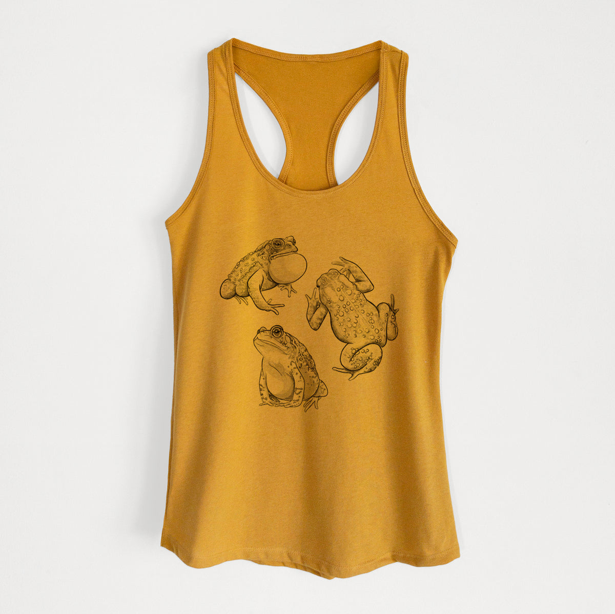 Gold women's racerback tank top laid flat, printed with a black ink illustration of three American toads.