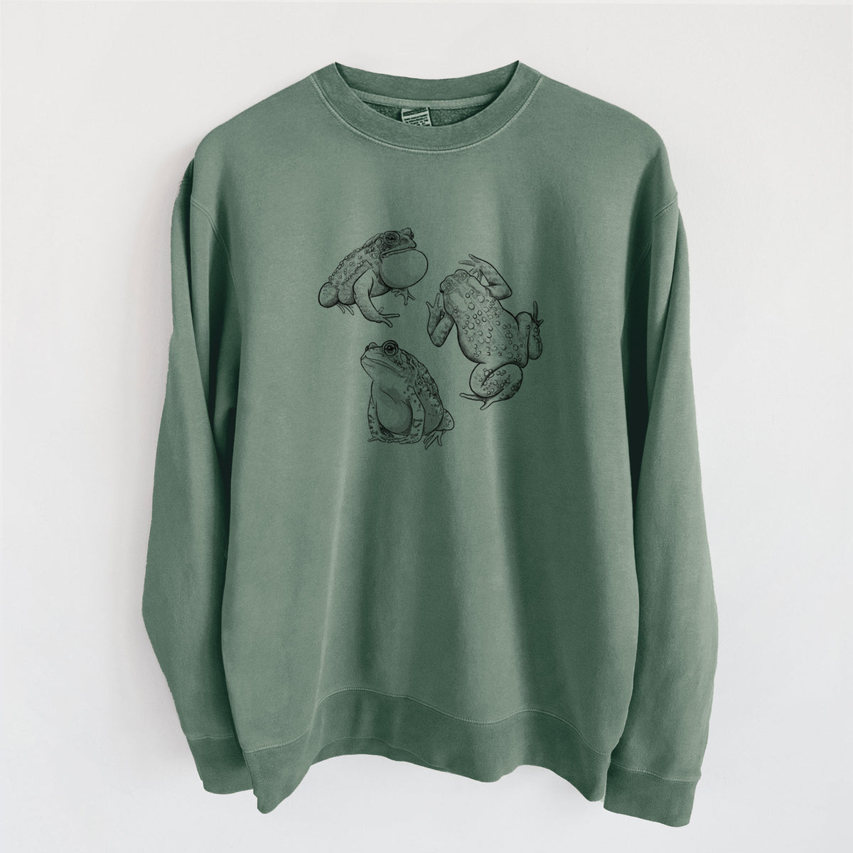 Alpine green pigment dyed crewneck sweatshirt laid flat, printed with a black ink illustration of three American toads.