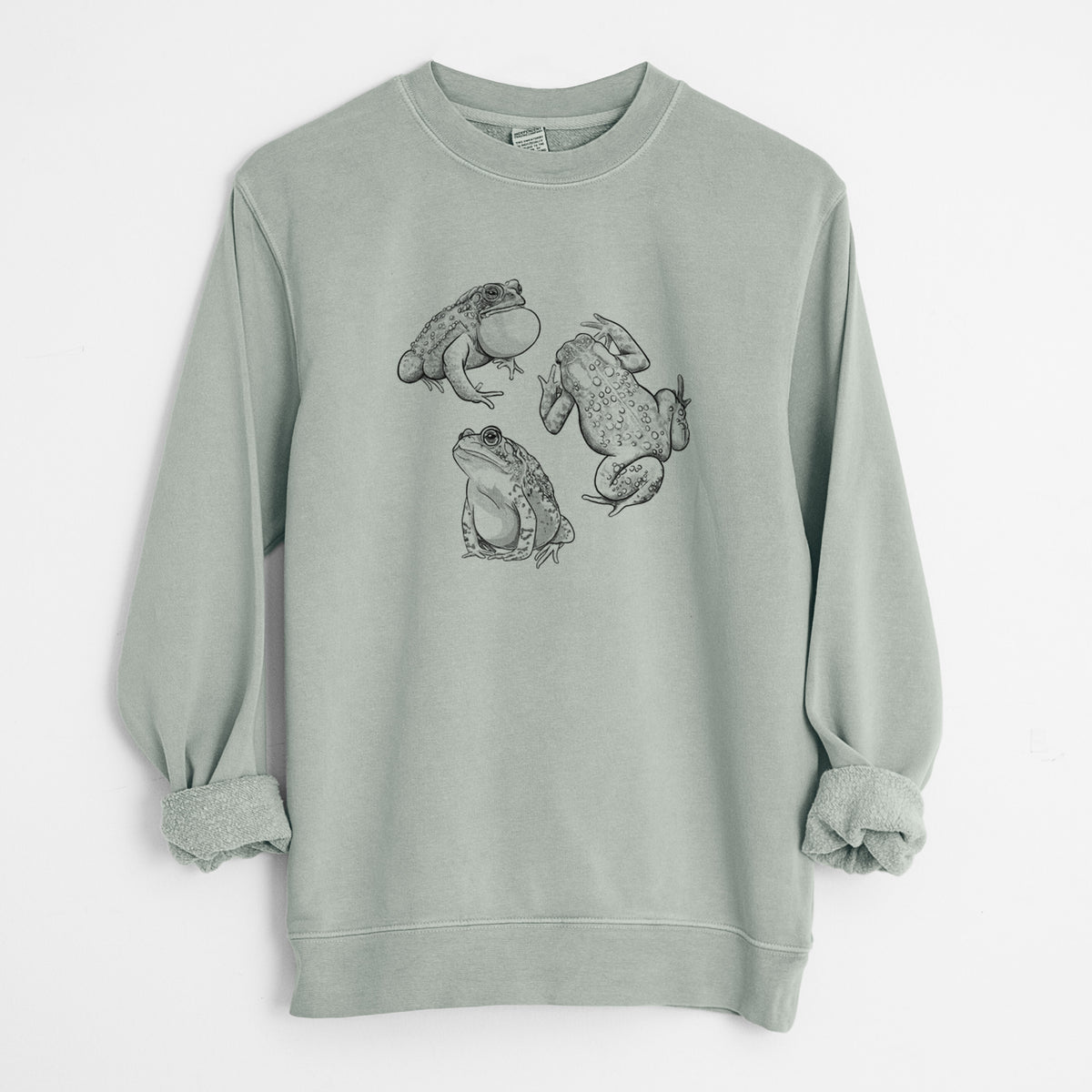 Sage green pigment dyed crewneck sweatshirt laid flat with the sleeves rolled, printed with a black ink illustration of three American toads.