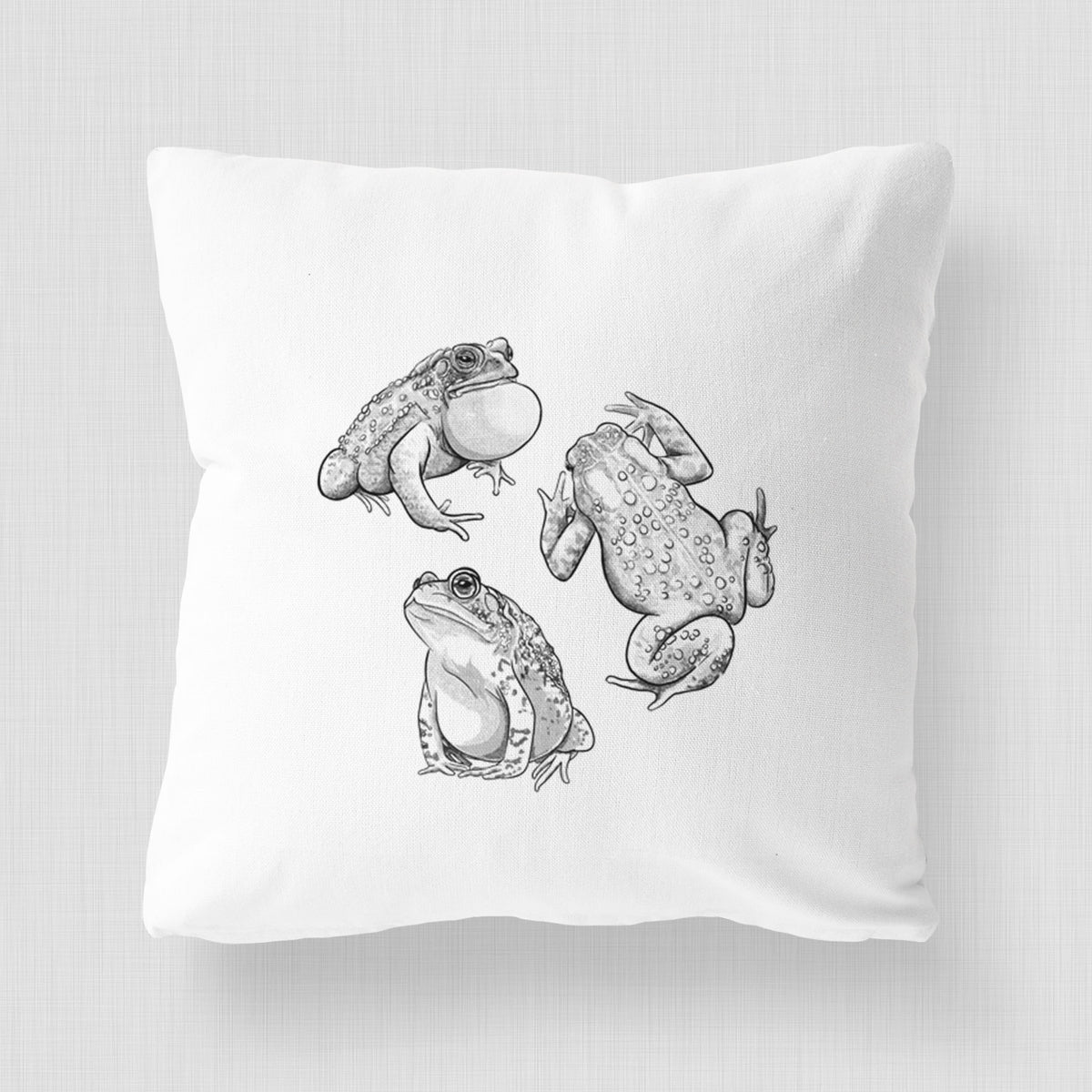White pillow cover printed with a black ink illustration of three American toads.