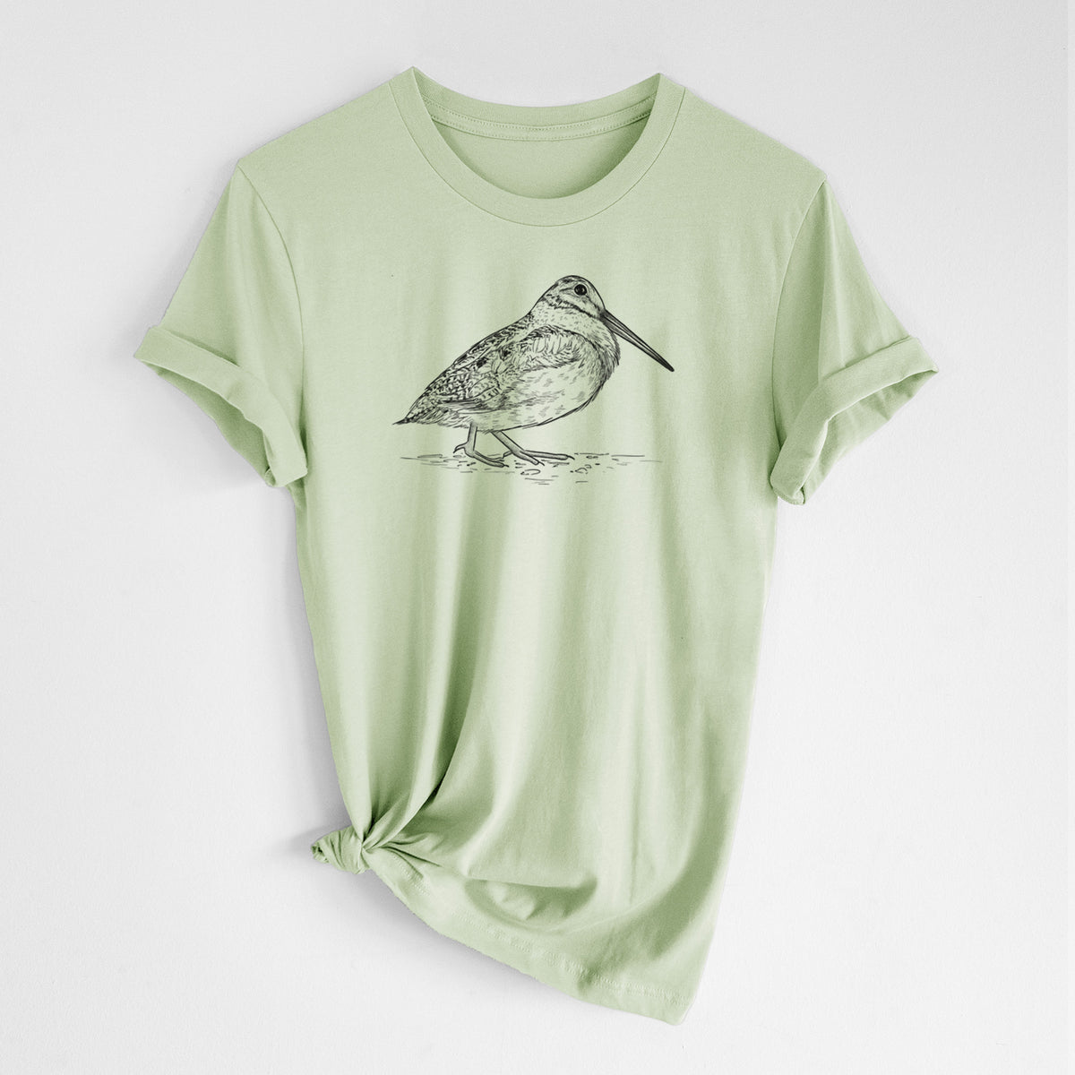Spring green lightweight cotton t-shirt laid flat with the sleeves rolled, printed with a detailed black ink sketch of an American woodcock standing on the ground.