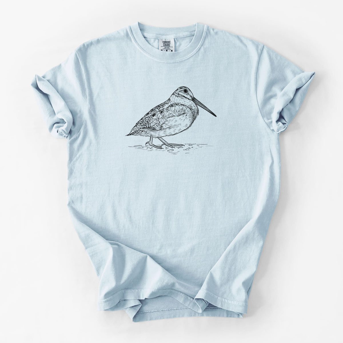 Chambray blue Comfort Colors t-shirt laid flat, printed with a detailed black ink sketch of an American woodcock standing on the ground.