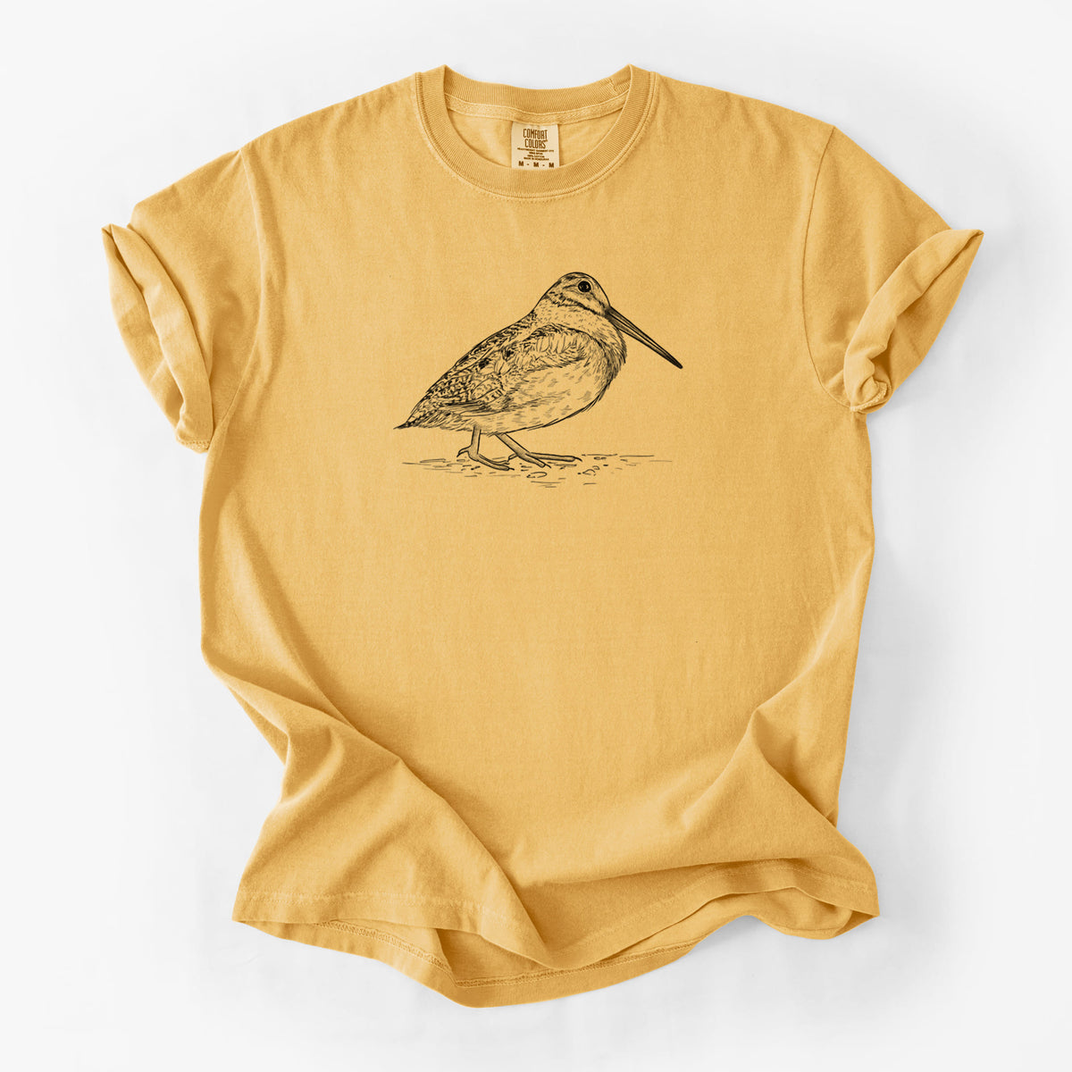 Golden wheat yellow Comfort Colors t-shirt laid flat, printed with a detailed black ink sketch of an American woodcock standing on the ground.