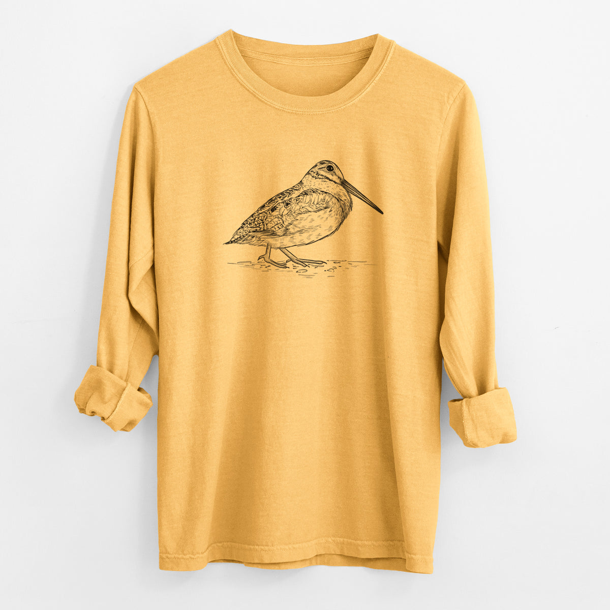 Golden wheat yellow Comfort Colors long sleeve shirt laid flat with the cuffs rolled, printed with a detailed black ink sketch of an American woodcock standing on the ground.