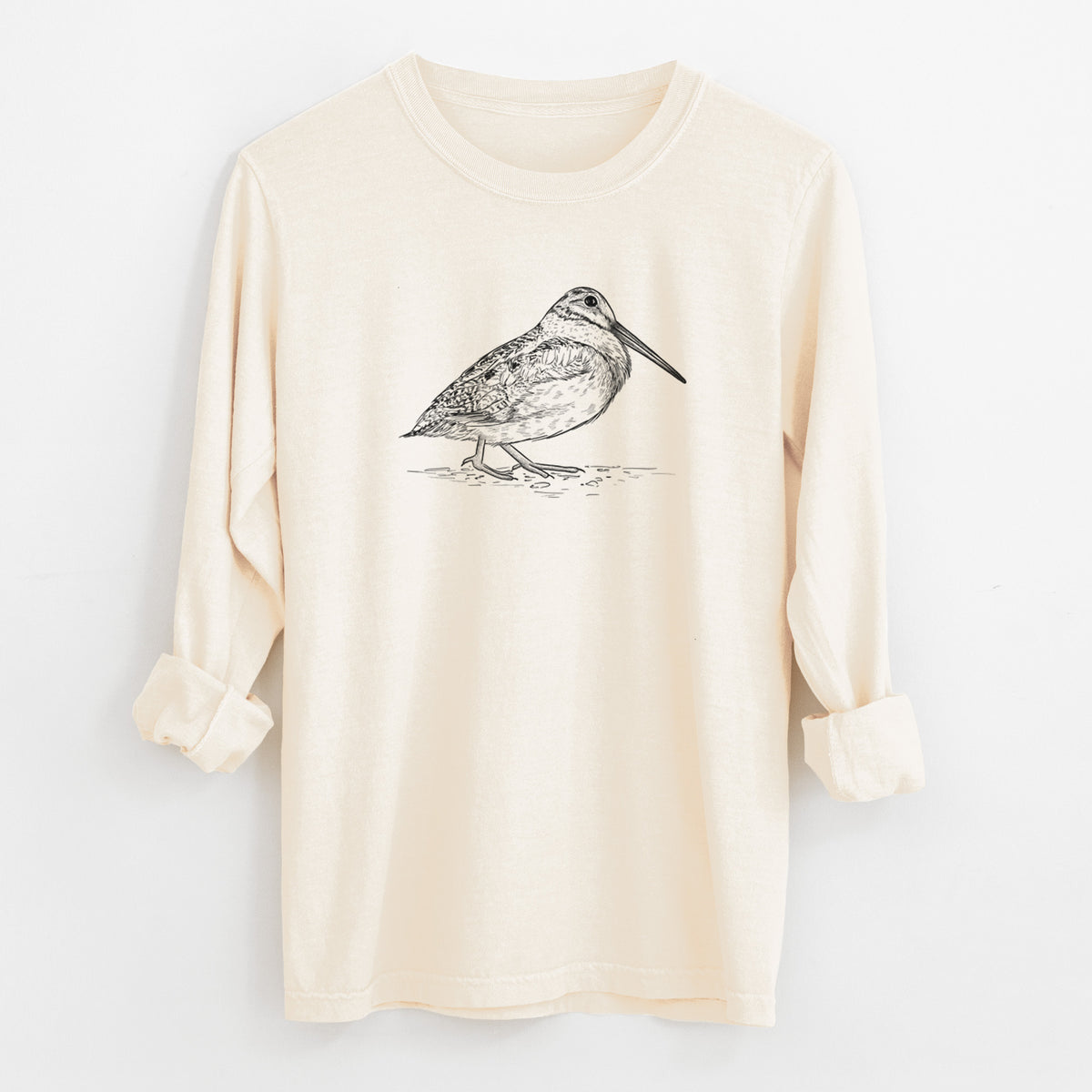 Ivory Comfort Colors long sleeve shirt laid flat with the cuffs rolled, printed with a detailed black ink sketch of an American woodcock standing on the ground.